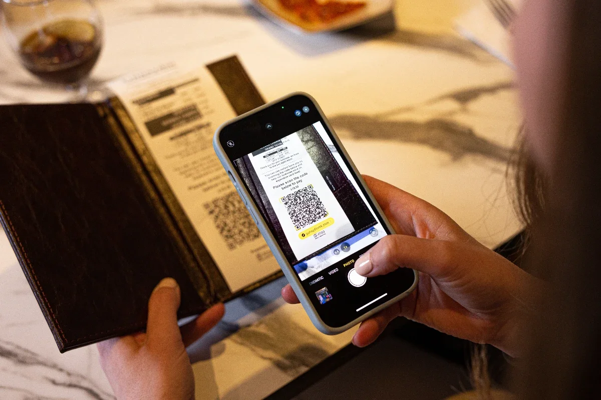 Person scanning a QR code on a menu with a smartphone at a restaurant or cafe.