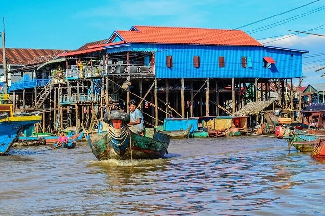 Stilt house by the water with boats and people around, in a coastal fishing village.