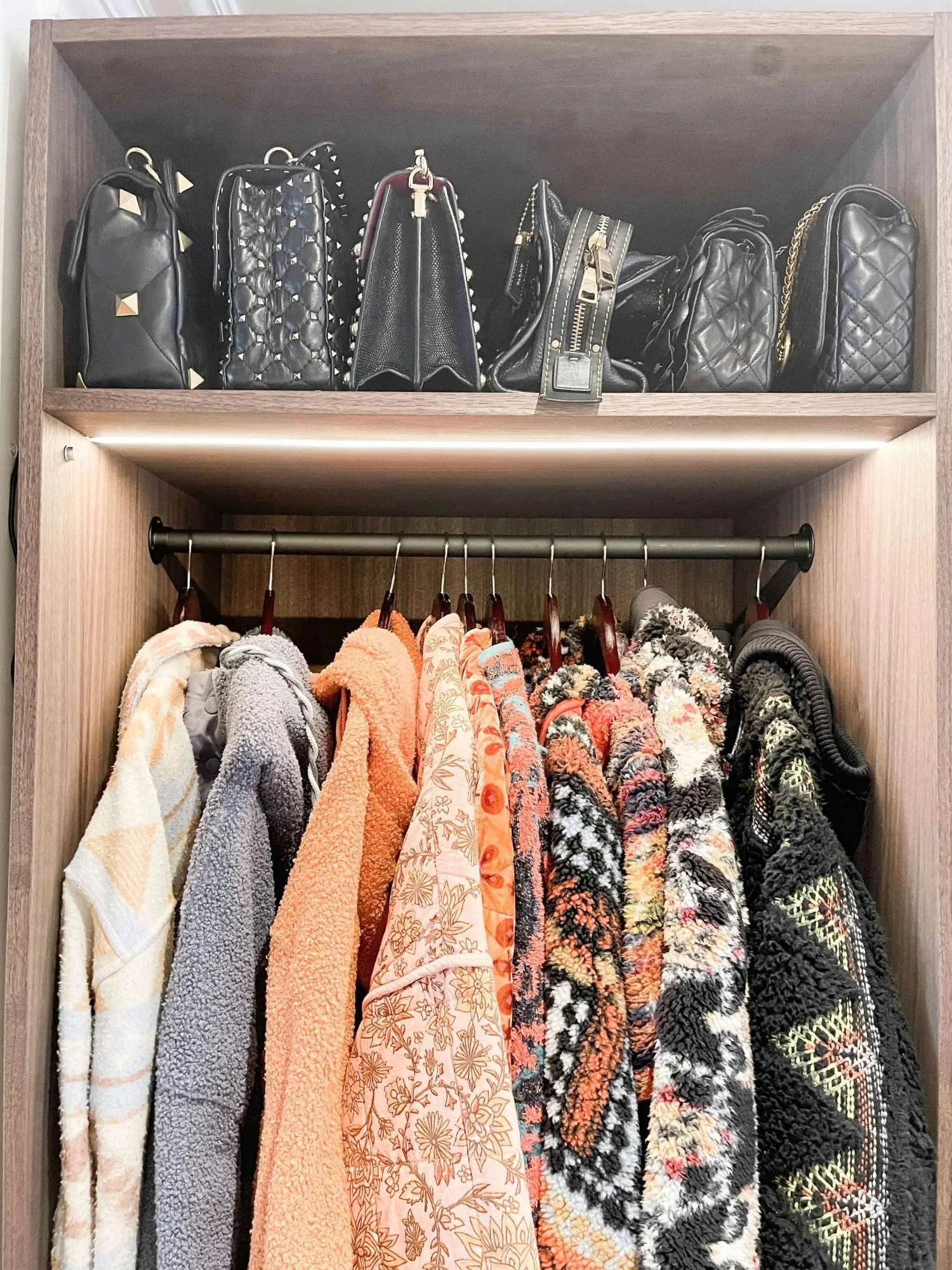 Coats and bags organised by colour in an entryway coat closet