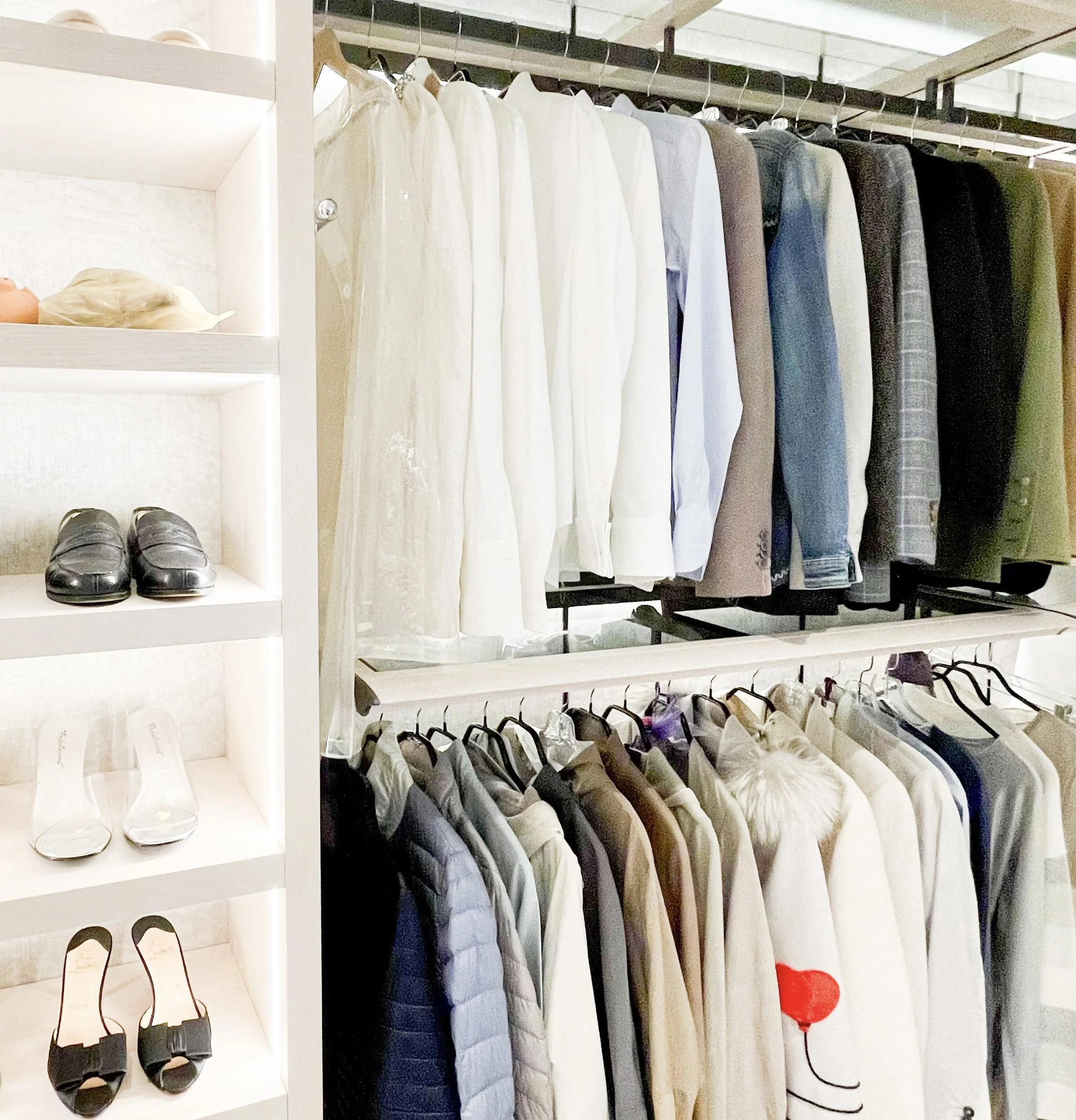 Organised wardrobe with neatly arranged hanging clothes and shoes displayed on open shelving.