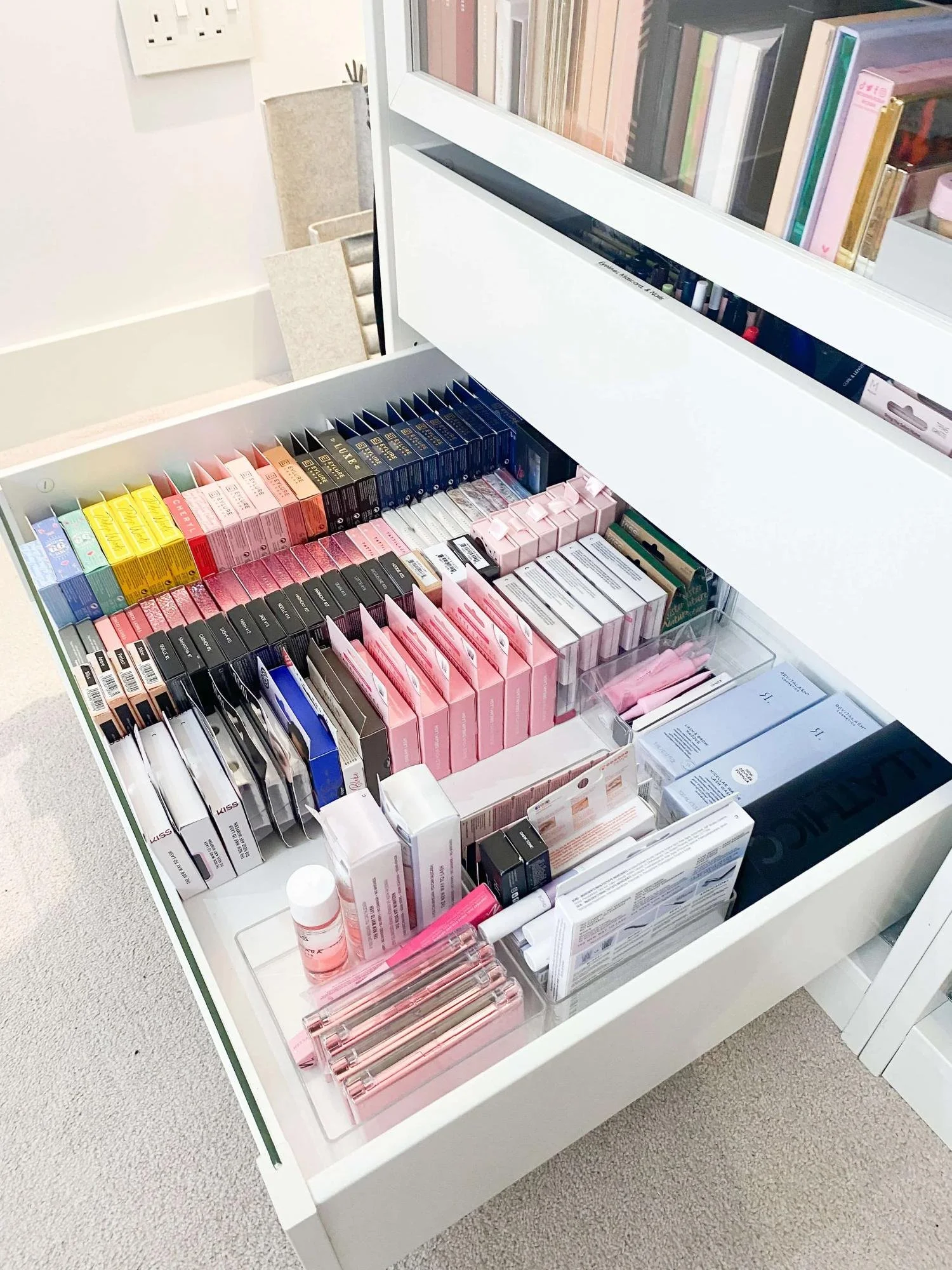 Makeup drawer organised with products in rows and by colour