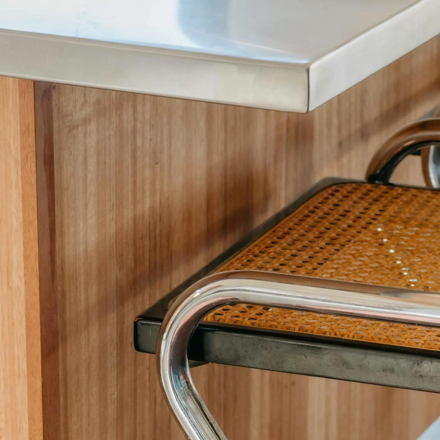 Wrapped stainless steel bench tops and and timber kitchen for our Guest House project. Cane and chrome cantilever bar stools from @smithstreetbazaar