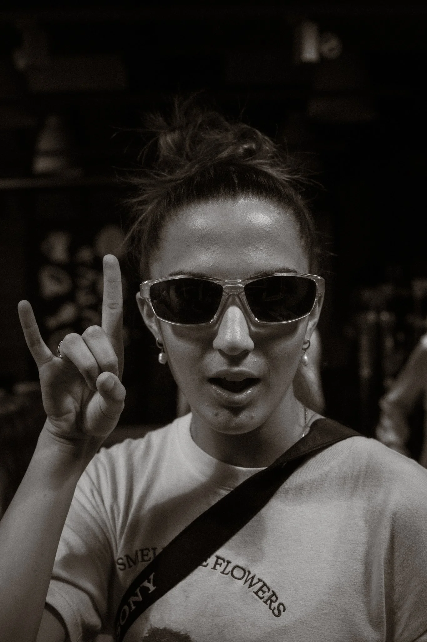 A woman wearing sunglasses making a rock and roll hand gesture while posing for the photo.