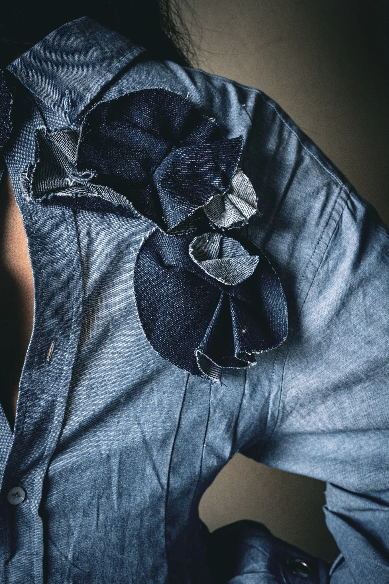 Close-up of a person wearing a dark gray or black shirt with fabric flower accents on the shoulder.