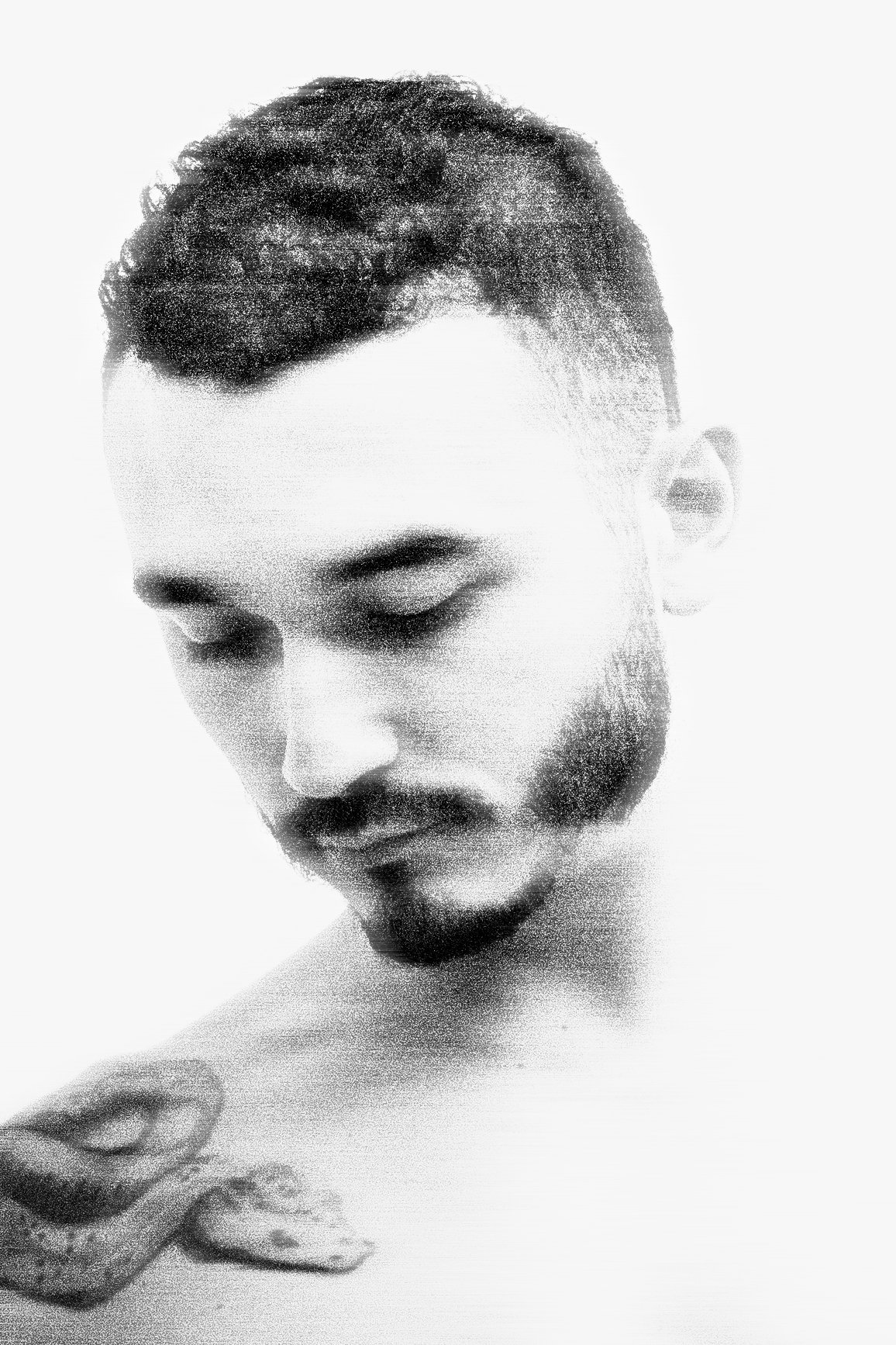 Black and white portrait of a man with short hair and a beard, looking down with a contemplative expression.