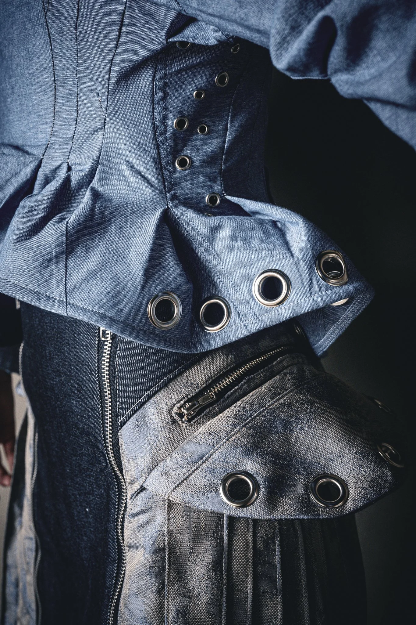 Close-up of metallic silver and black jackets with eyelet details and zippers.