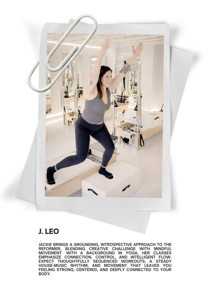 Woman in workout clothes exercising with arms raised in a Pilates studio with reformer equipment.
