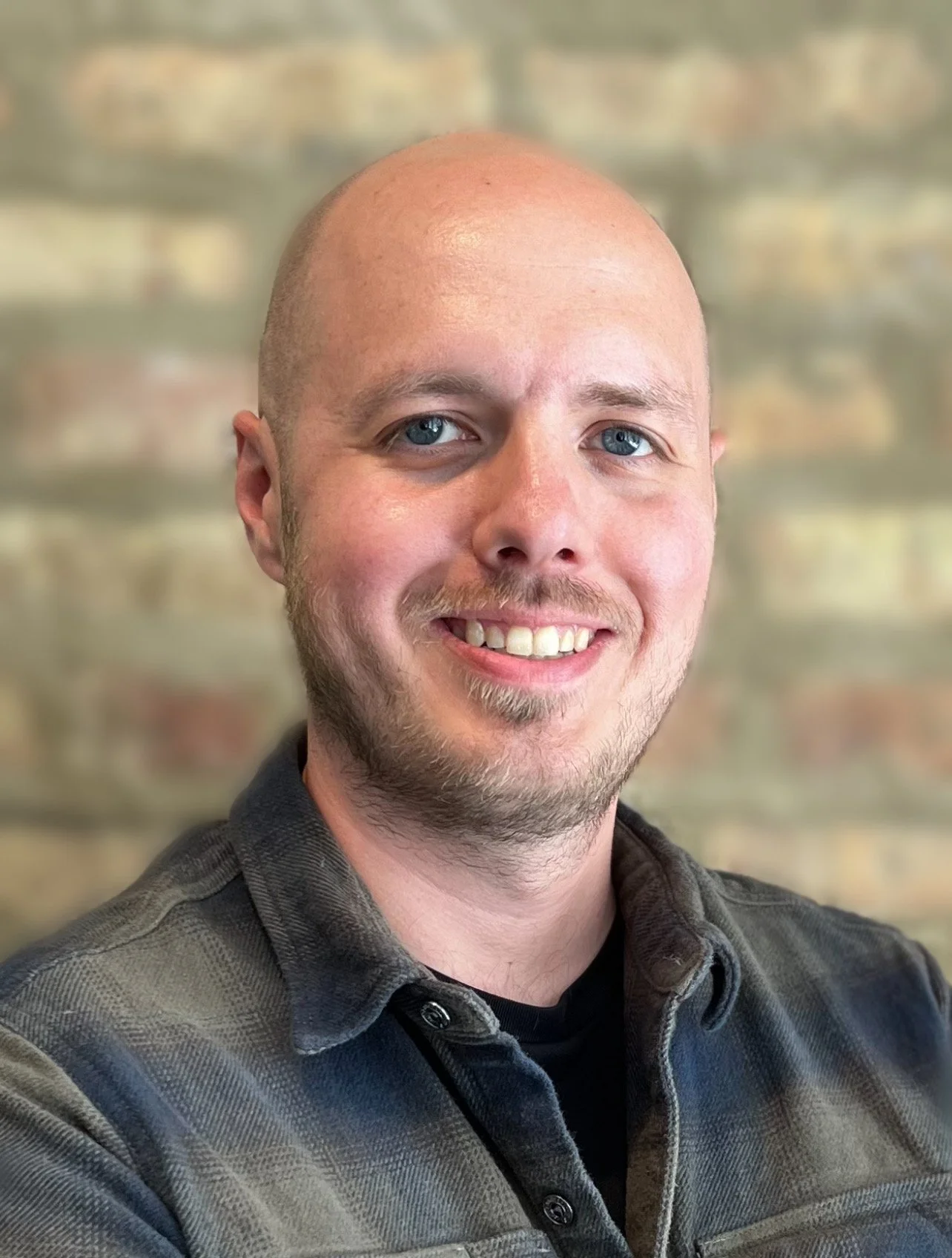 Matthew Sooby, MS, therapist for men and teens, at InPowered Therapy, smiling at the camera against a brick wall background.