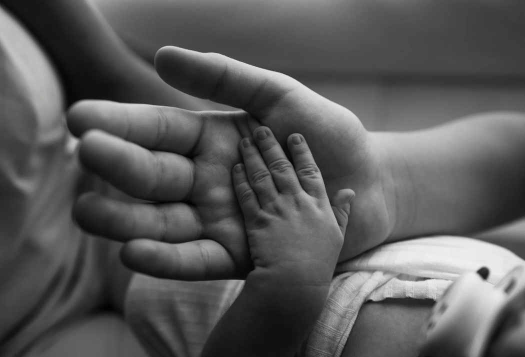 Baby hand resting in parents hand