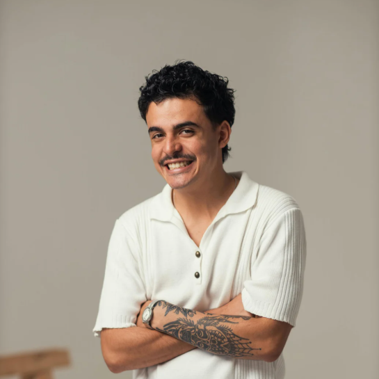 Man with tattoos crossing his arms and smiling