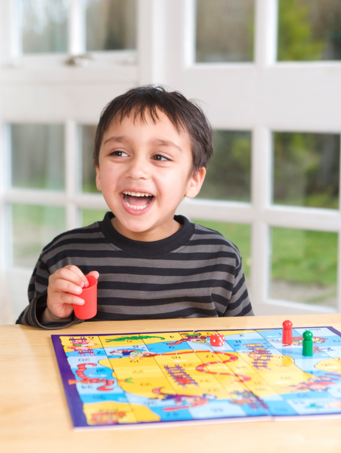 Smiling boy rolling dice for a board game