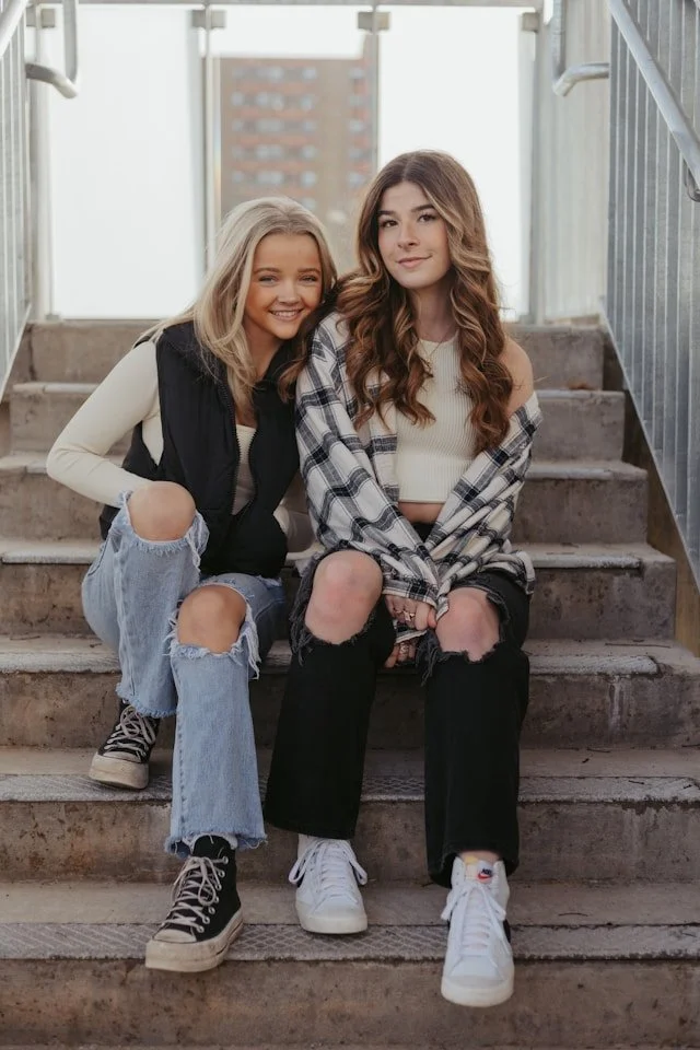 Two Teenage Girls Smiling while sitting next to each other