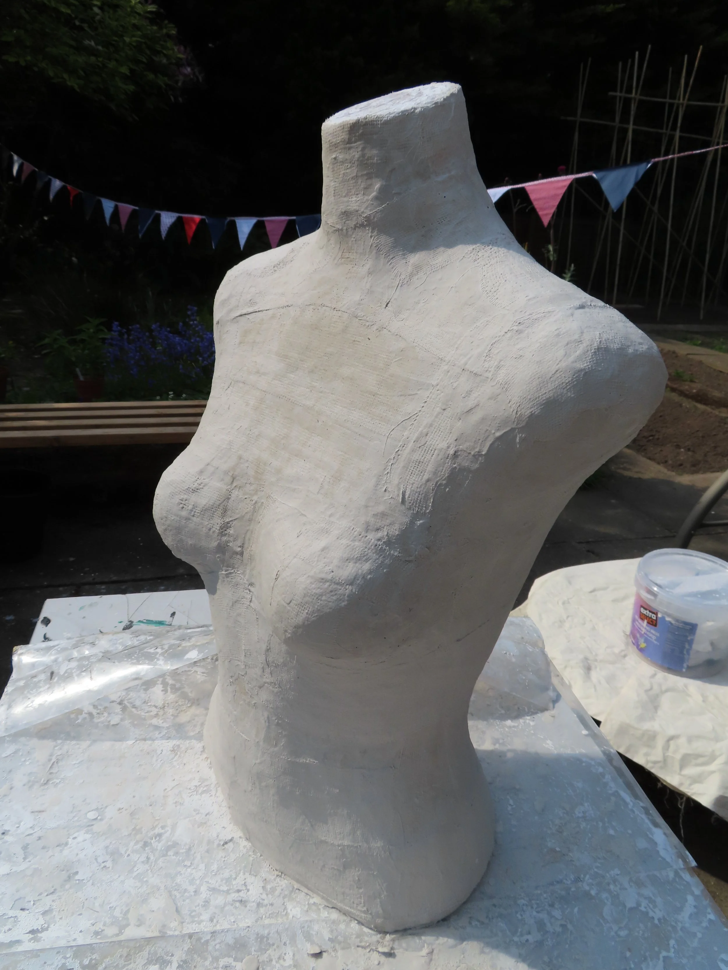 The hollow torso cast reassembled and upright again, completely white and unpainted. The rough plaster surface is visible and the neck opening at the top is exposed, ready for the next stage of construction.