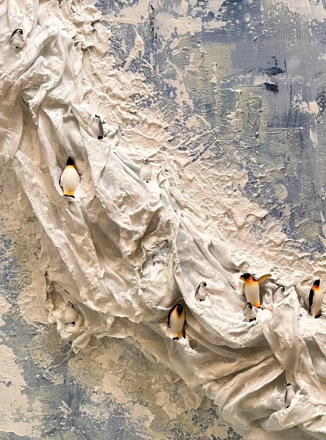 A close-up of the ledge and penguins showing the texture and brush swirls, pale layers, and deep blue markings.