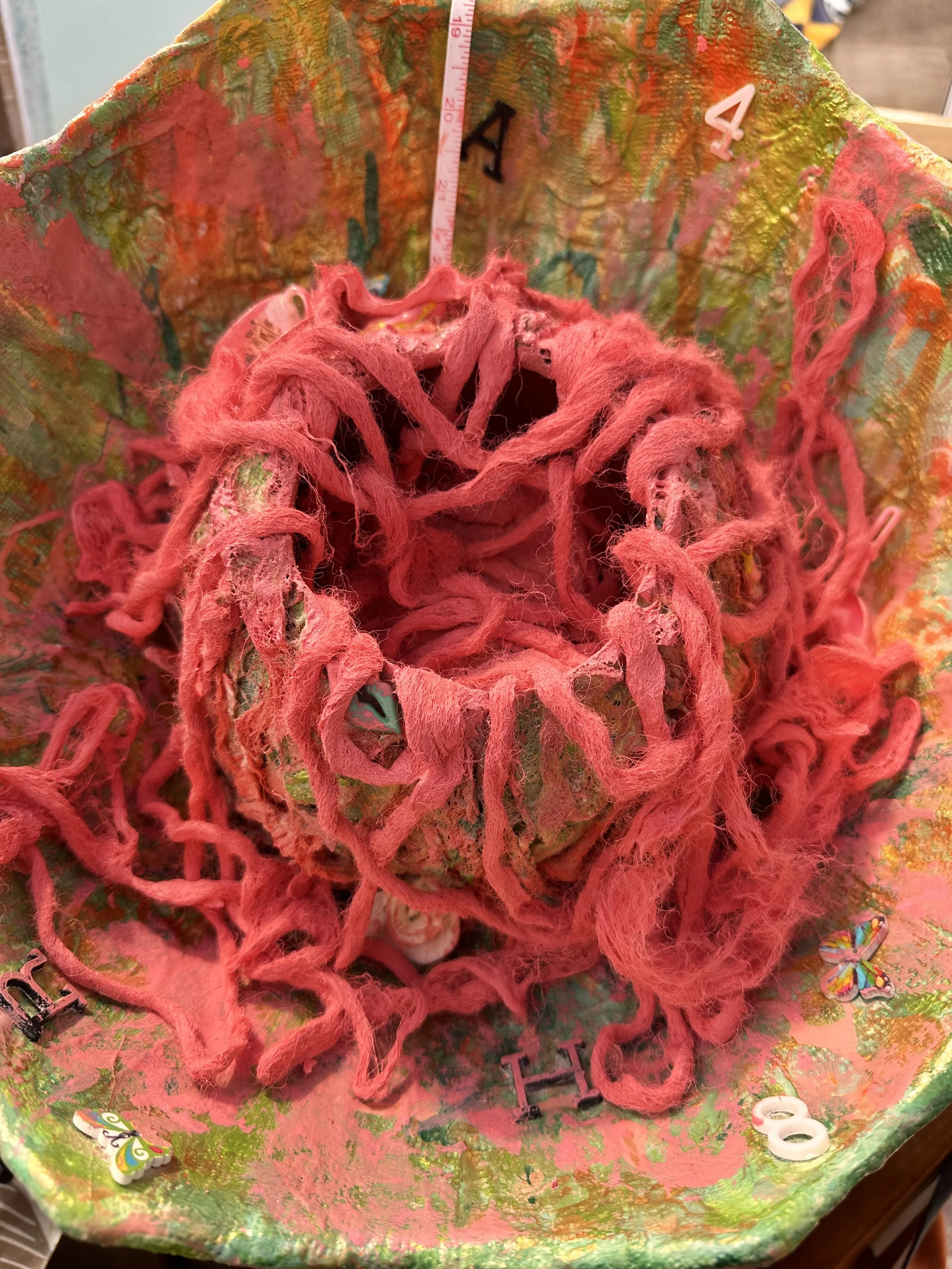 close up detail of the central brain section of the sculpture with the top having been cut off and pink painted wool spilling over the edges