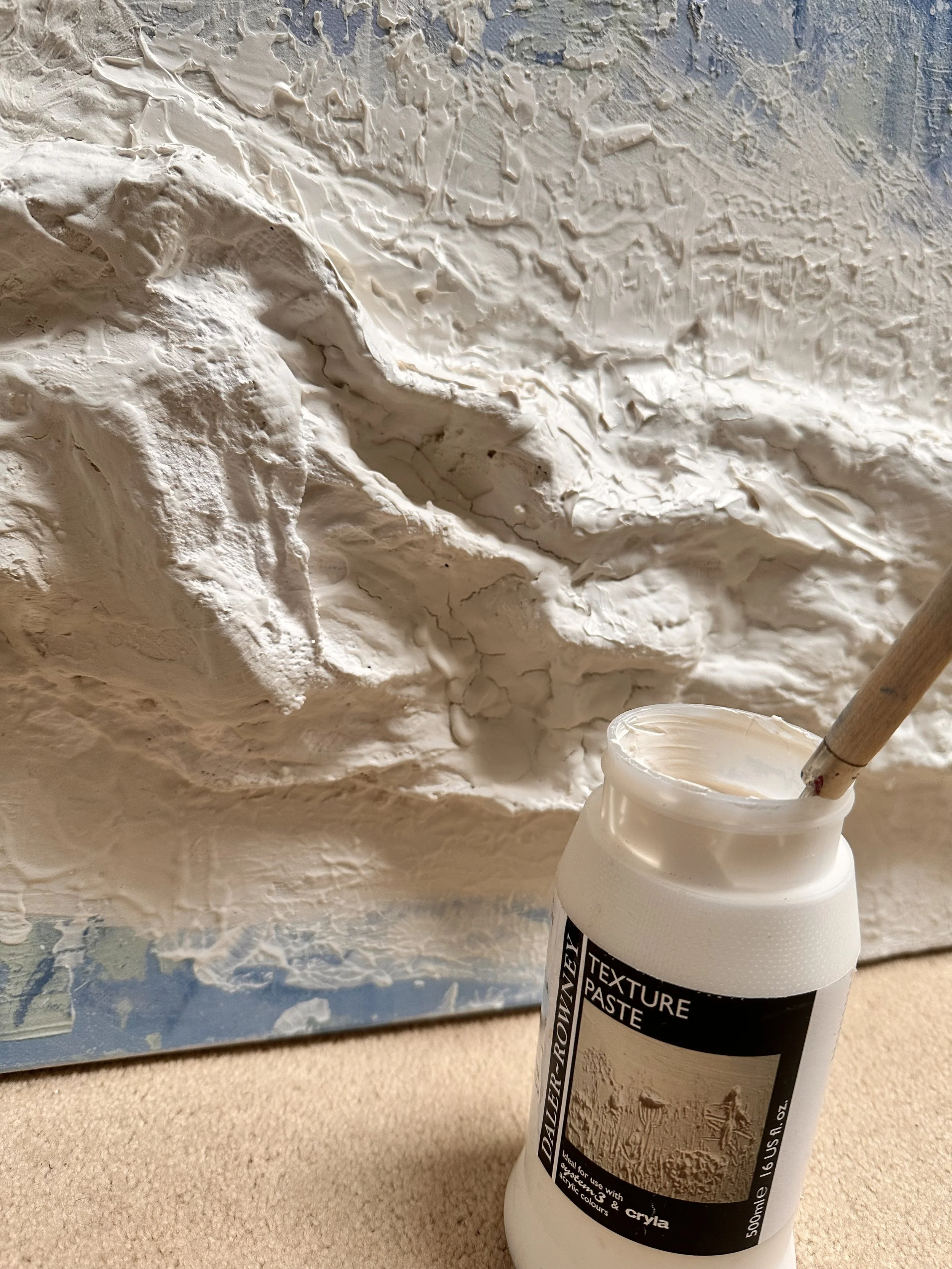 close-up detail of the Daler-Rowney texture paste jar and brush, mid-application onto the snowy wire constructed ledge. sitting on a cream carpet