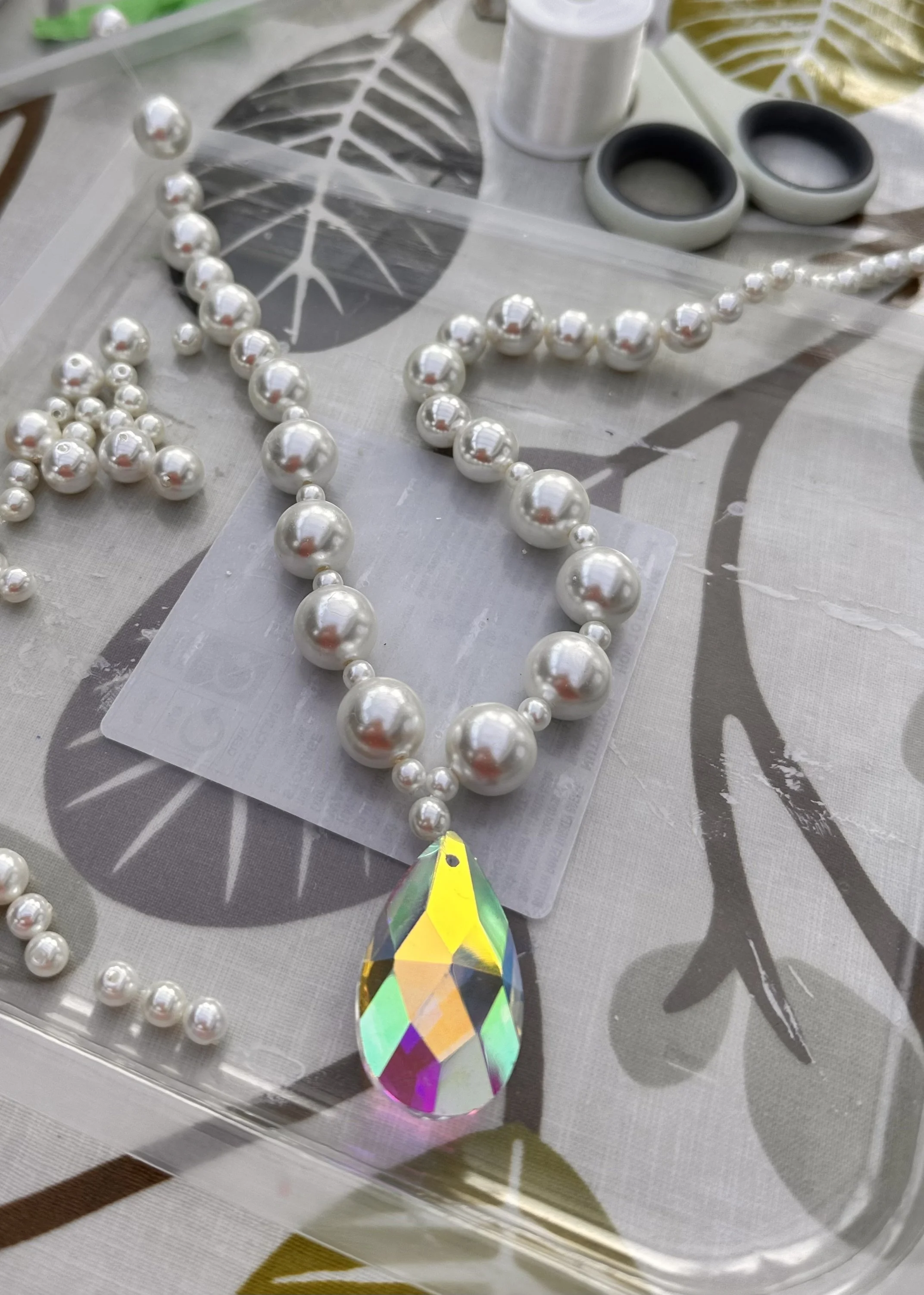 crystal drops and pearls arranged on a patterned tablecloth – the early planning stage of the sculpture ‘i identify as fabulous darling’.
