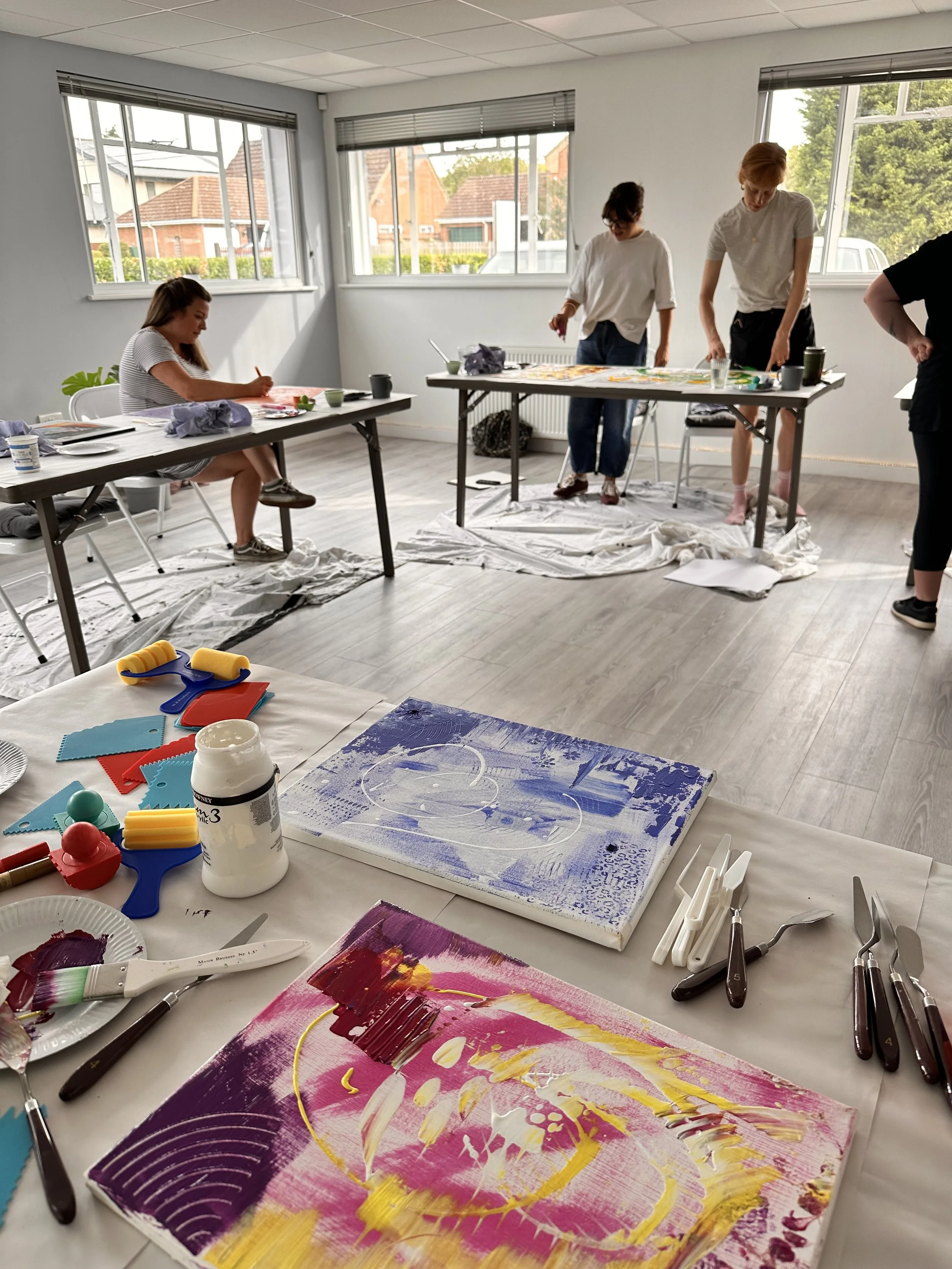 People standing and sitting at tables painting