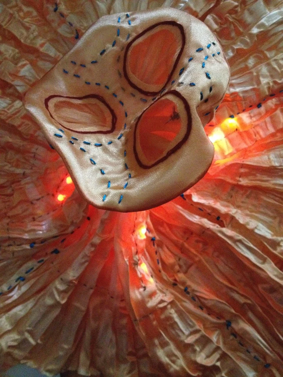 orange shibori shaped puppet with three eyes