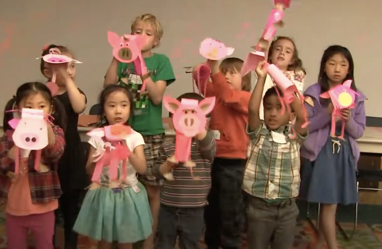 Children holding handmade pig puppets at a pupet pop up workshop 