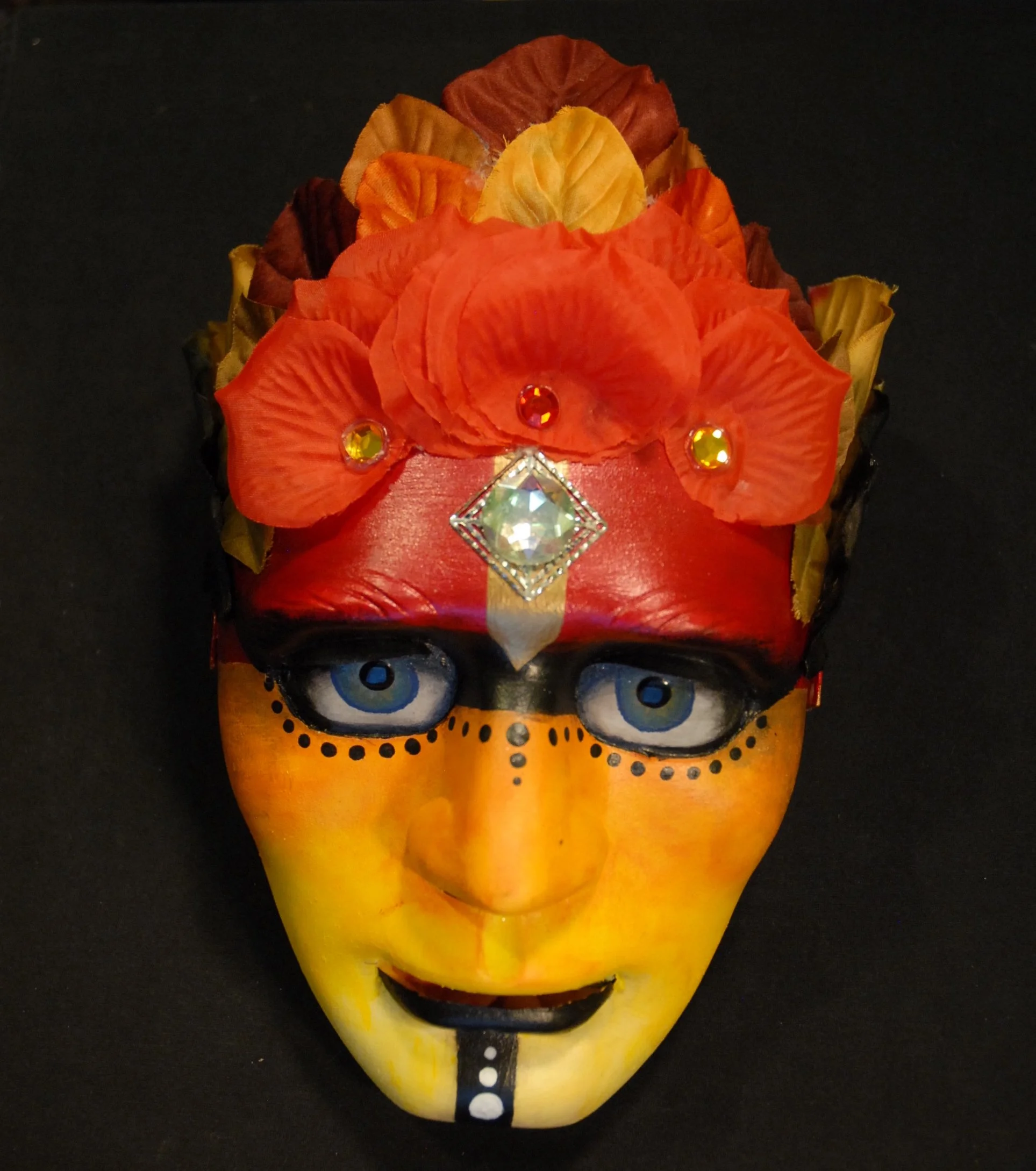 Dramatic red orange mask with green eyes outlined in dots. Red leaves are used for the hair