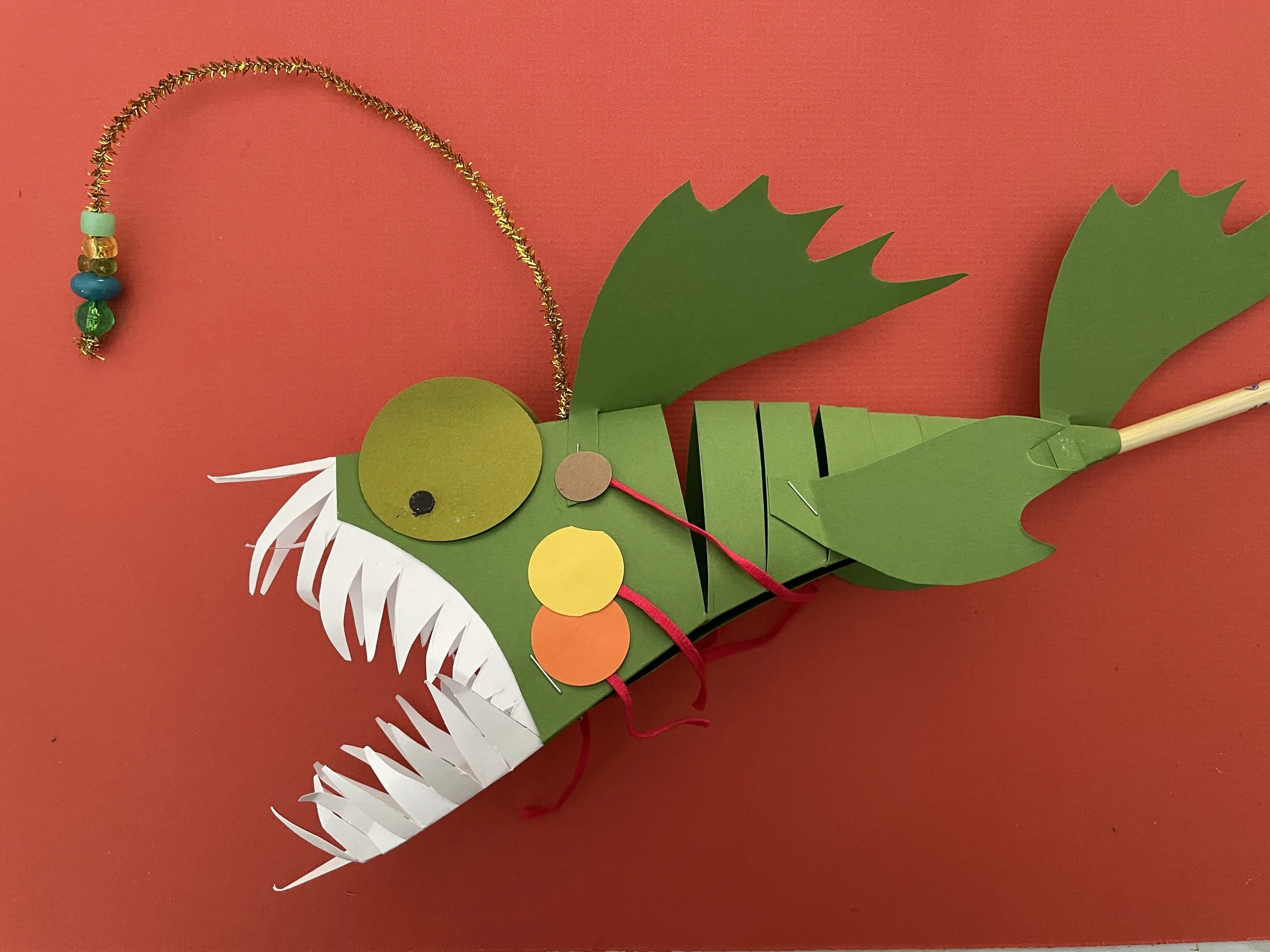 Folded green paper puppet of an angler fish 