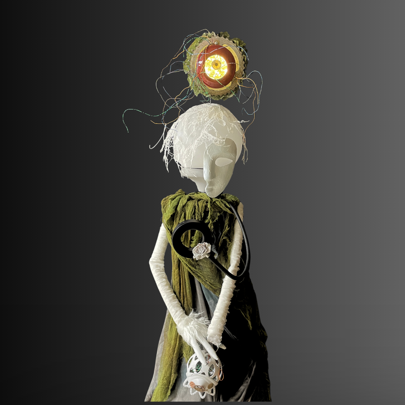 white puppet face with clothing and a glowing bulb with red surround 