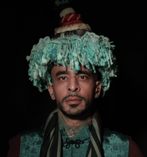Dark skinned man wears a tufted turquoise hat 