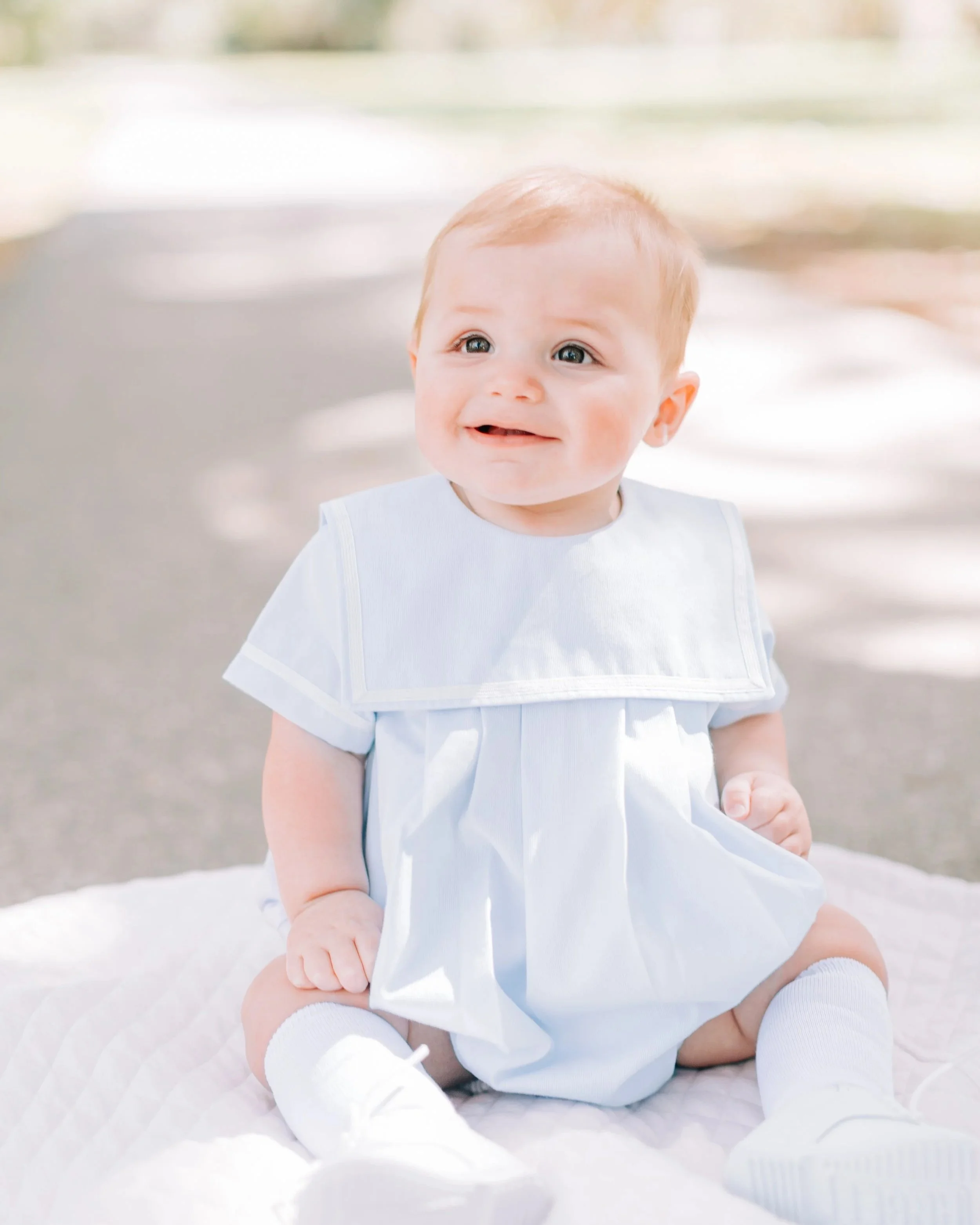 Baby sitting on blanket outdoors smiling during Baton Rouge family photography session