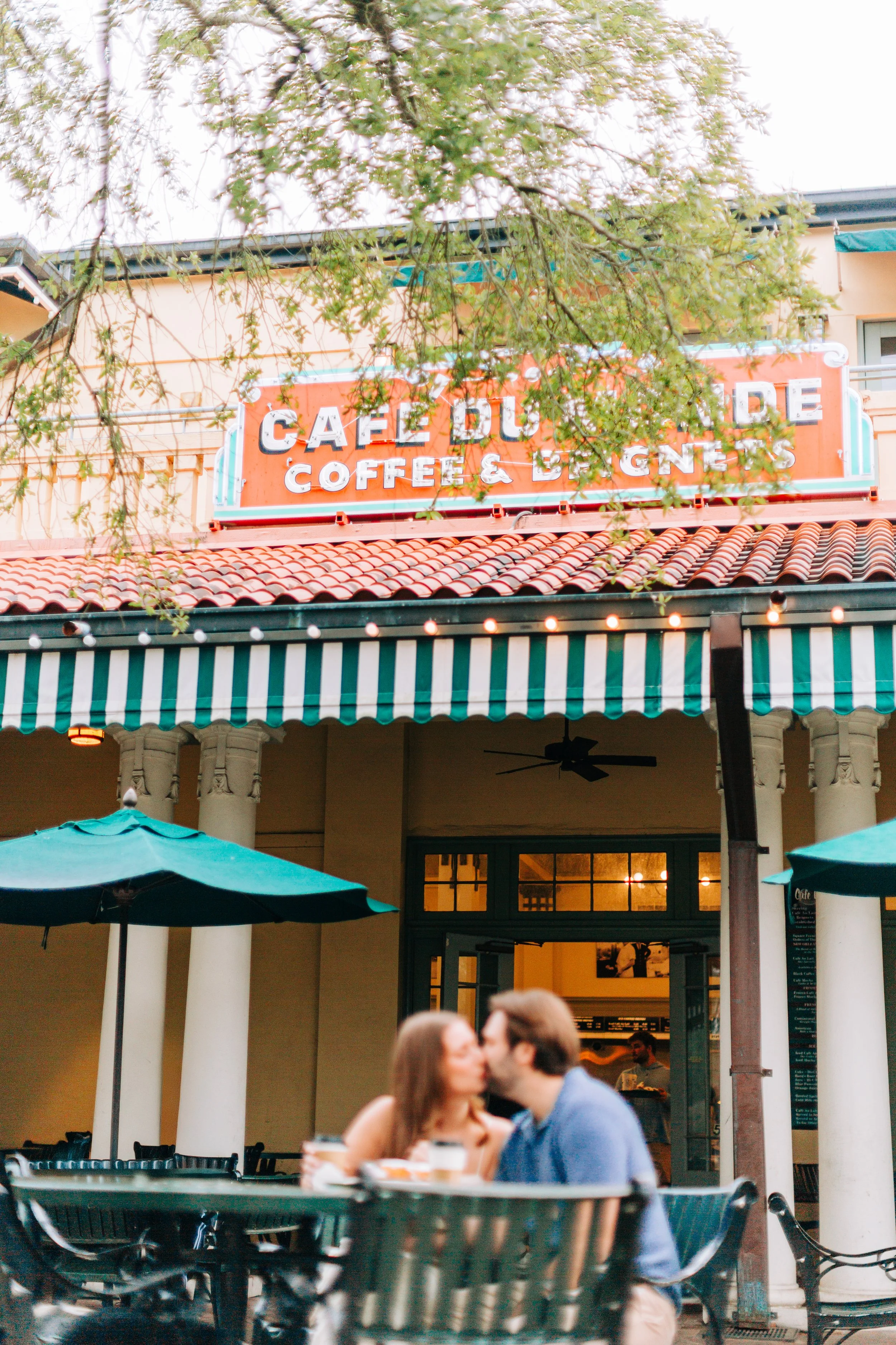 couple having coffee at cafe du monde during engagement photography with sarah shaw
