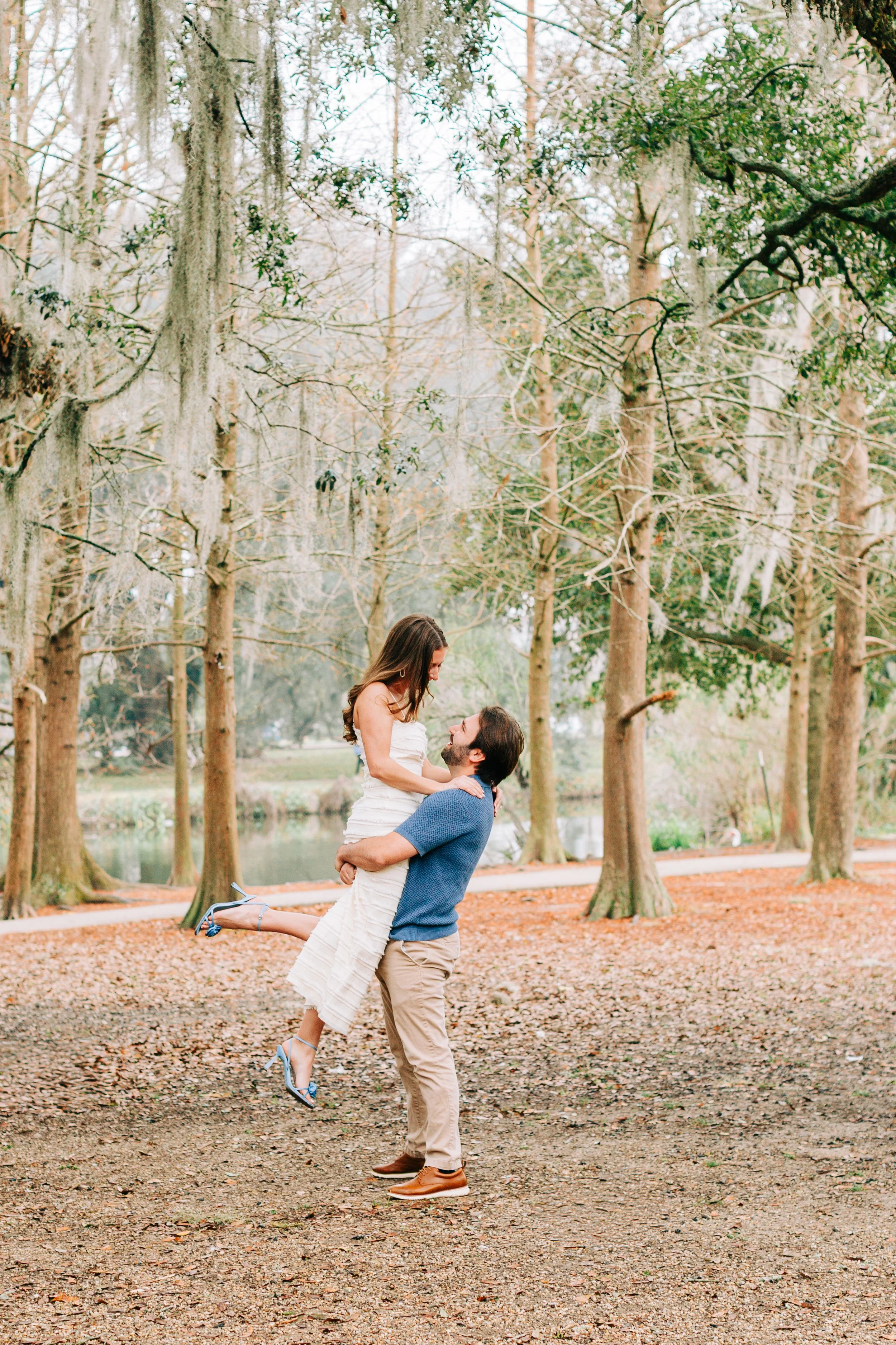 victoria and patrick’s new orleans city park engagement photos, man lifting woman off the ground in city park,baton rouge wedding photography