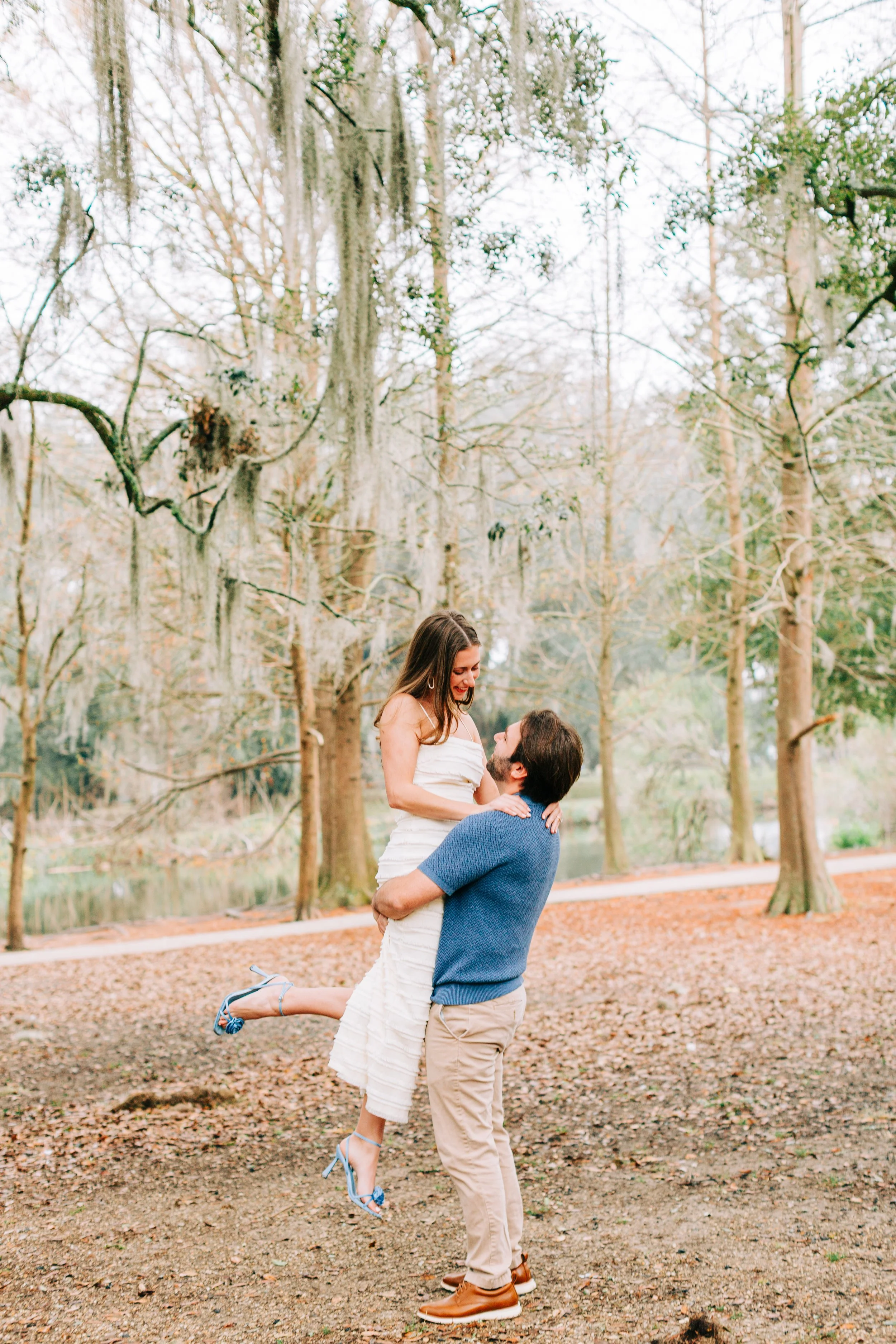 victoria and patrick’s new orleans city park engagement photos, man lifting woman off the ground in city park, baton rouge wedding photography