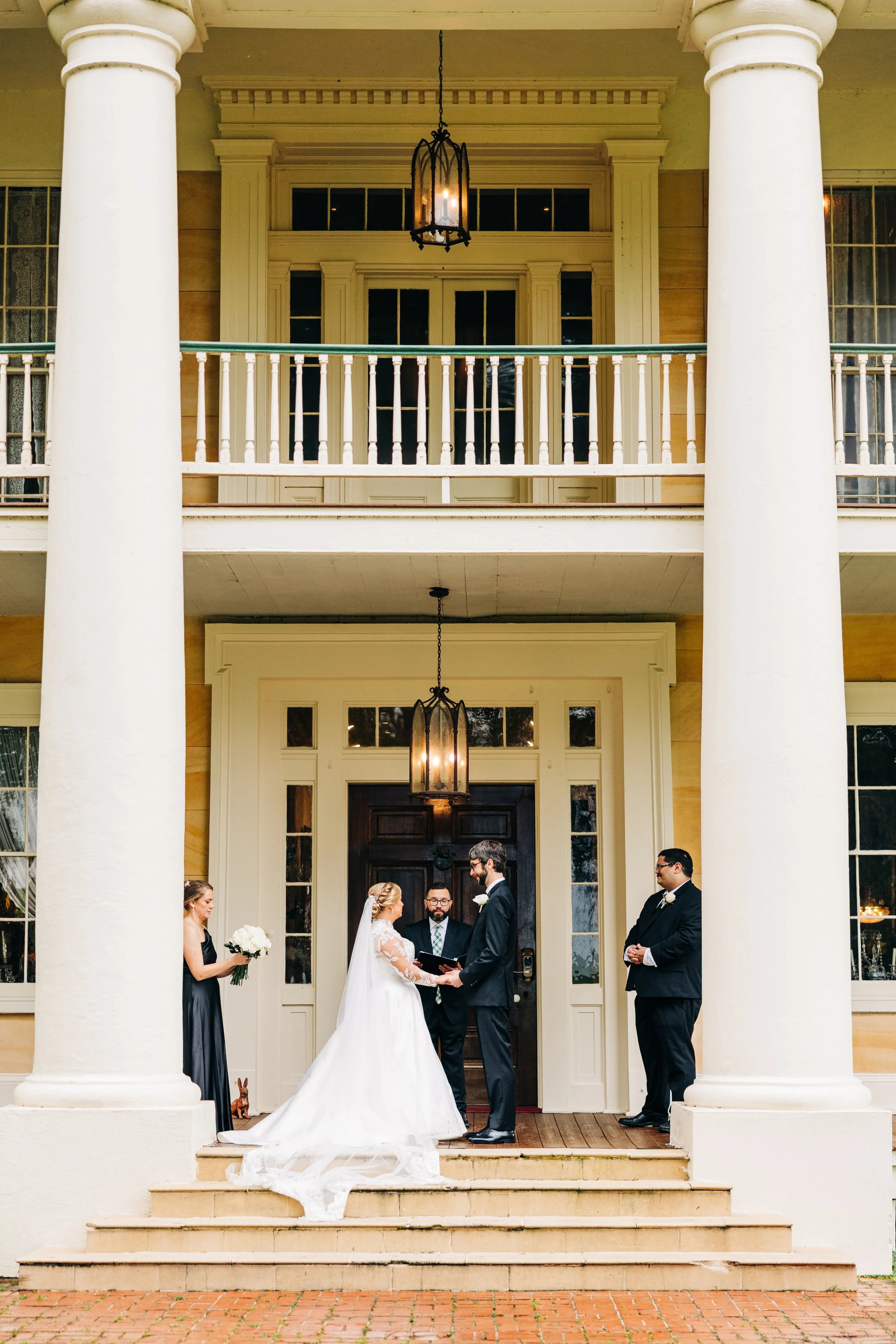 bride and groom on the front porch of houmas house during outdoor wedding ceremony in spring, exchanging vows, baton rouge wedding photography