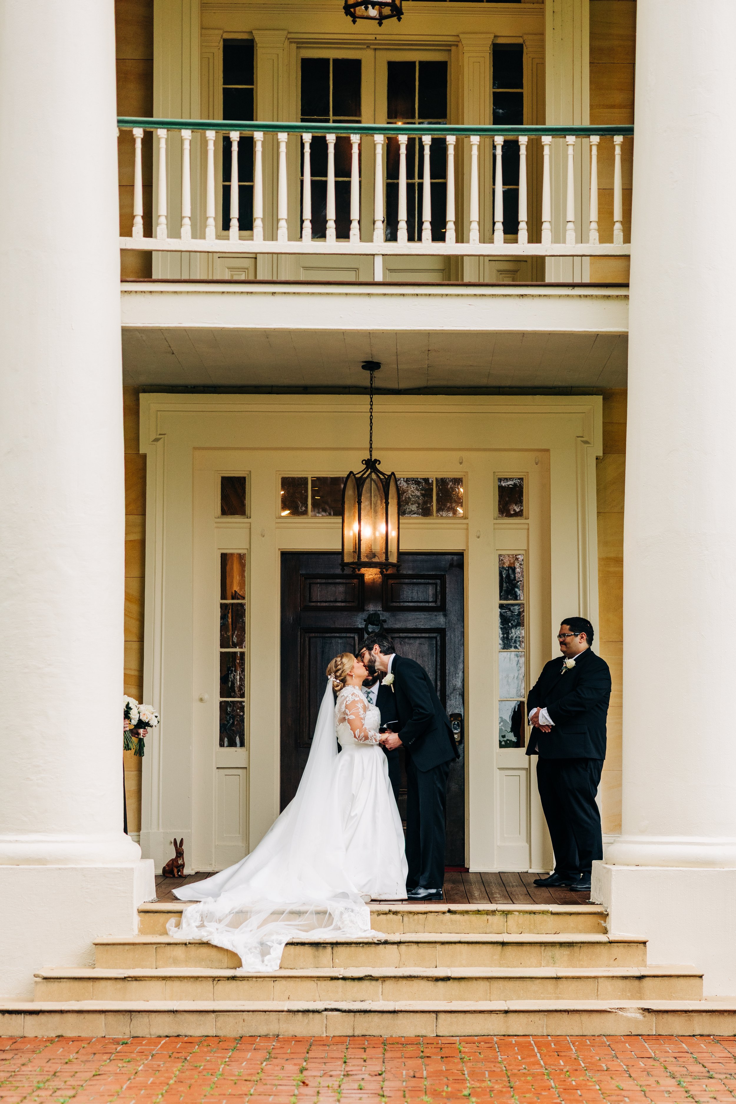 bride and groom’s first kiss on the front porch of houmas house during outdoor wedding ceremony in spring, baton rouge wedding photography