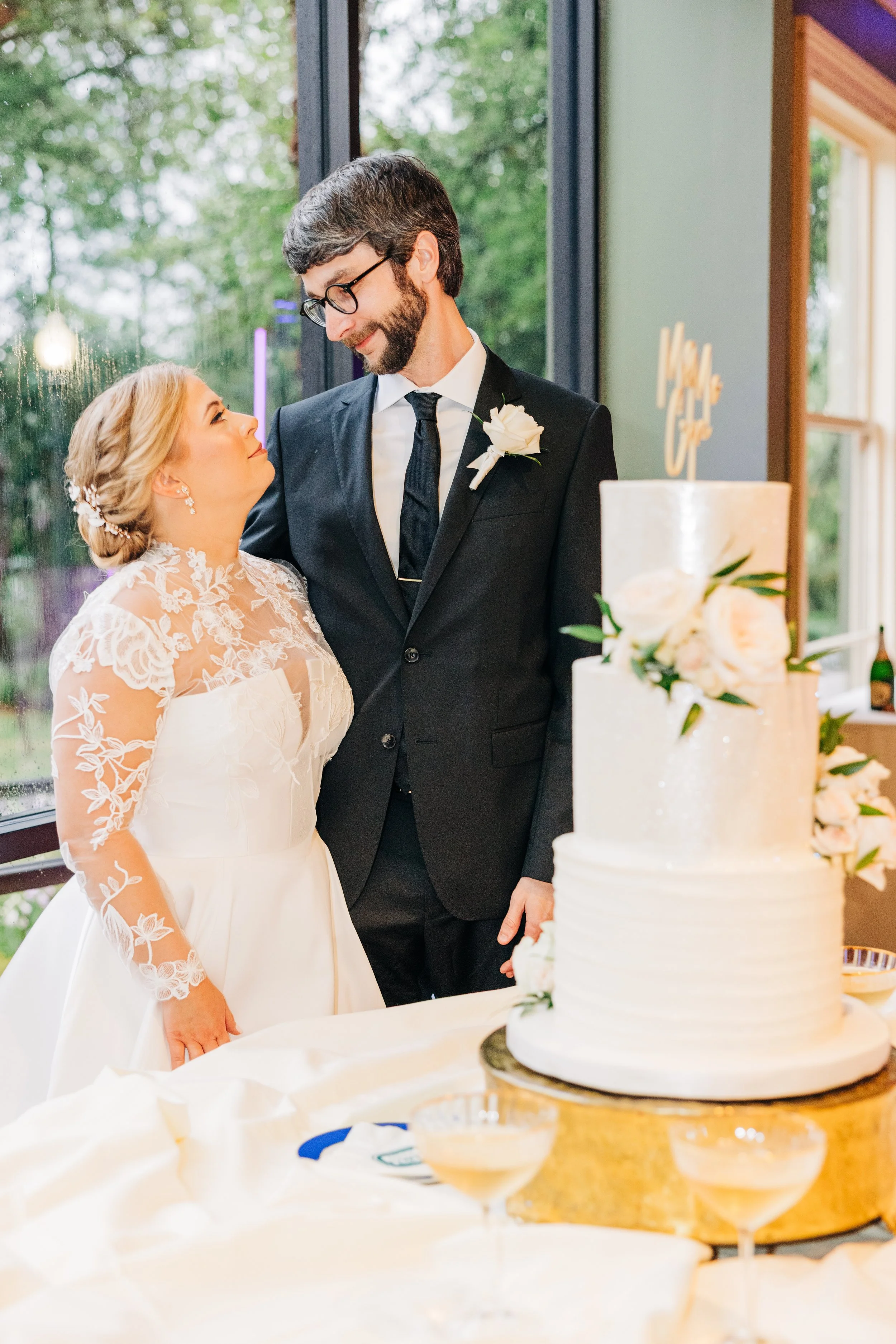 bride and groom smile at each other next to the wedding cake at the wedding reception in the neptune at houmas house, baton rouge wedding photography