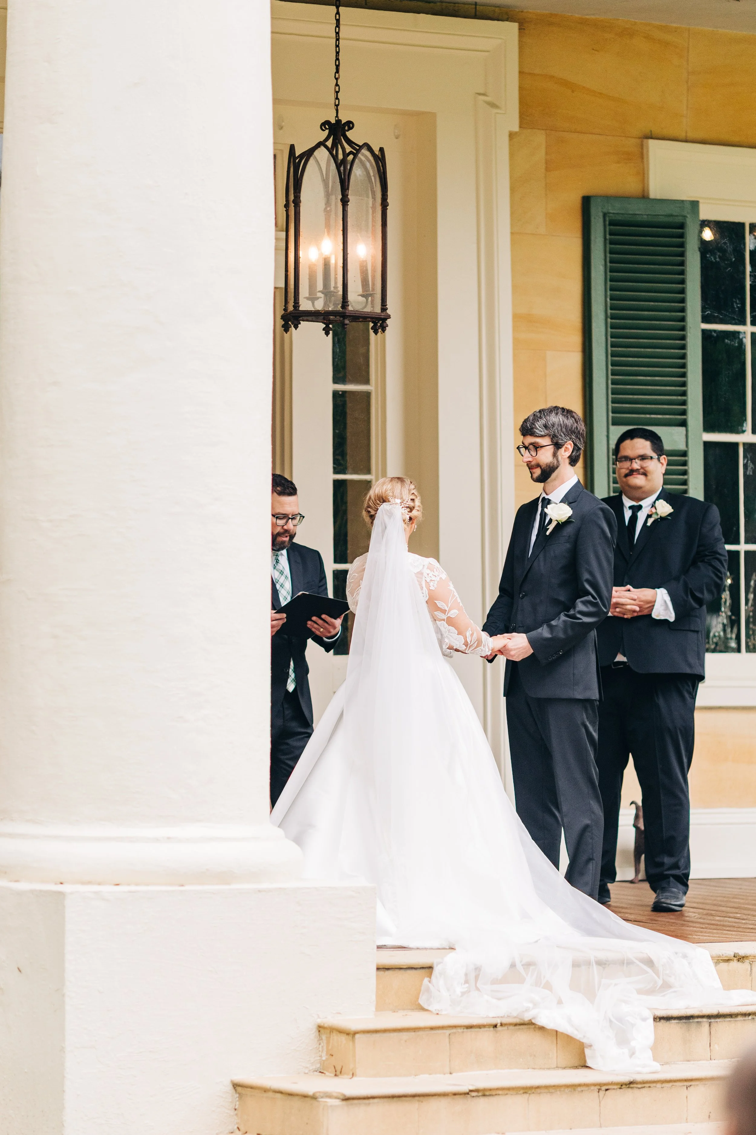 bride and groom on the front porch of houmas house during outdoor wedding ceremony in spring, exchanging vows, baton rouge wedding photography