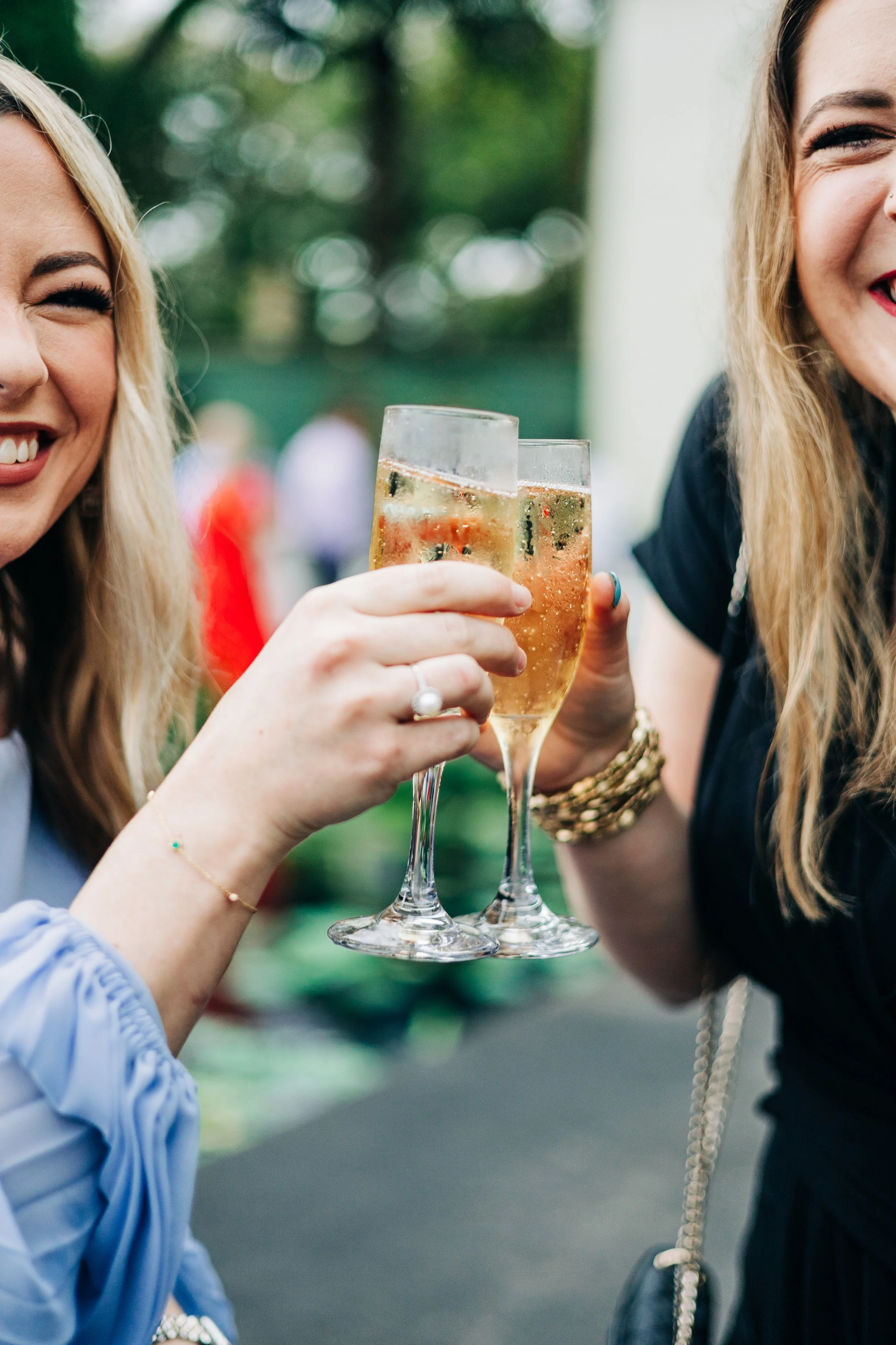girls holding champagne to cheers each other during outdoor cocktail hour at houmas house wedding in spring, baton rouge wedding photography