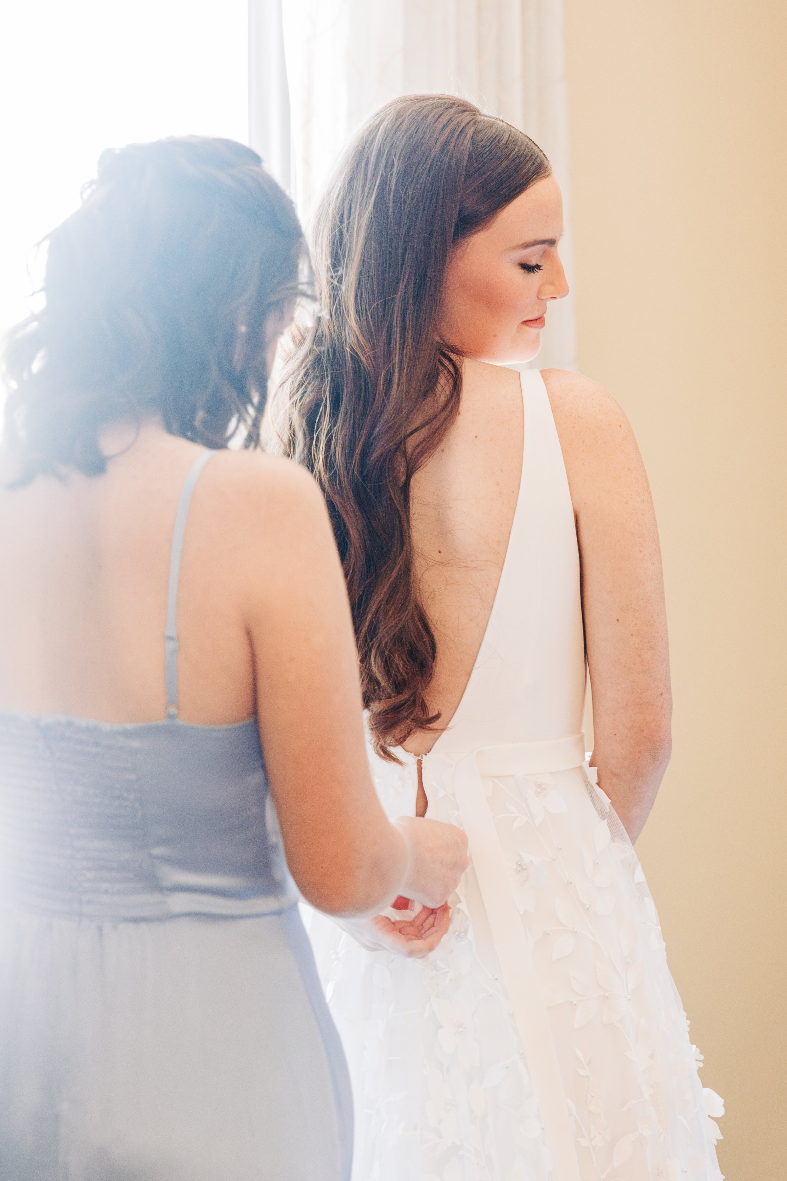 Bride putting on wedding dress in bridal suite at Baton Rouge wedding