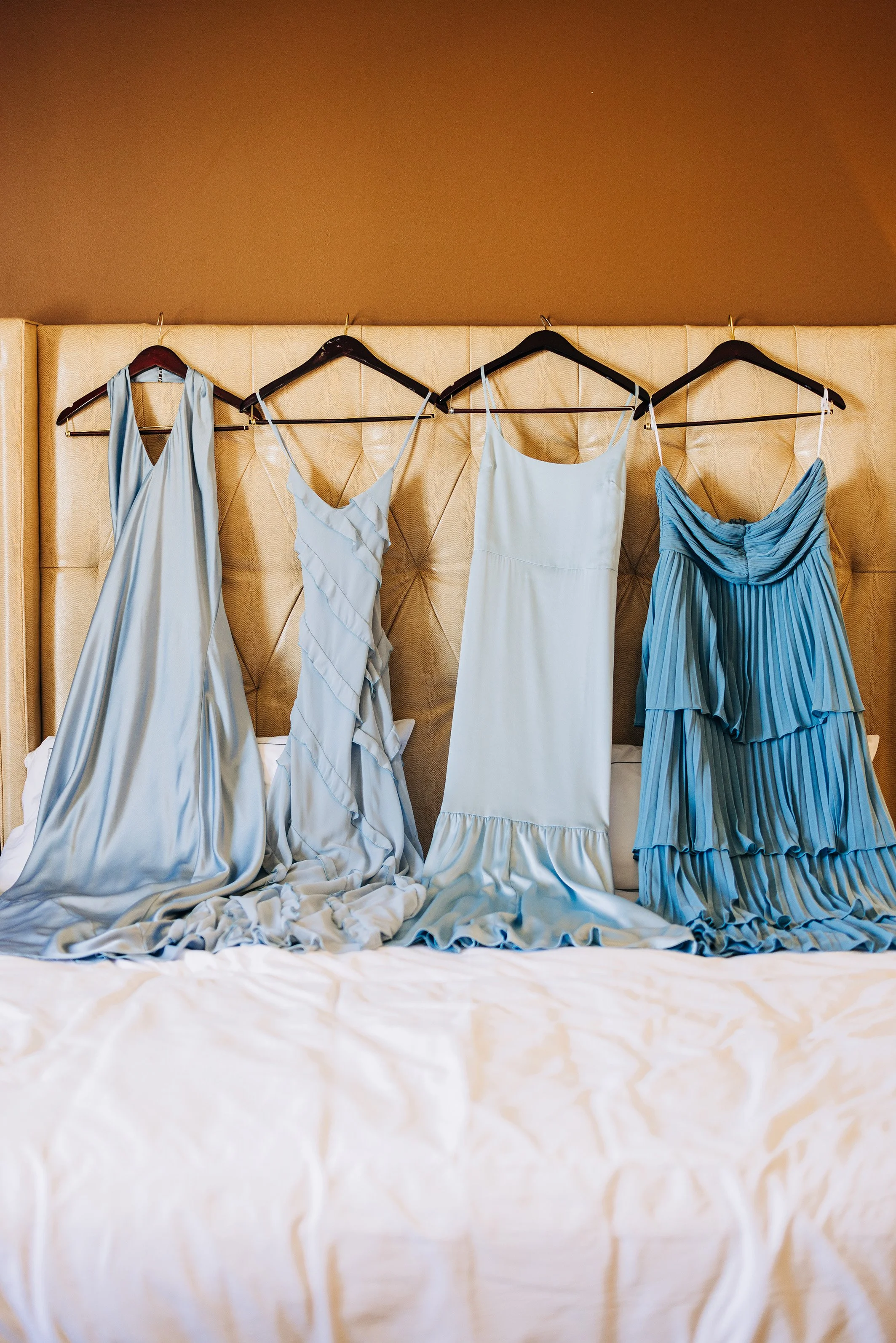 Bridesmaids dresses hanging on headboard during getting ready in the bridal suite