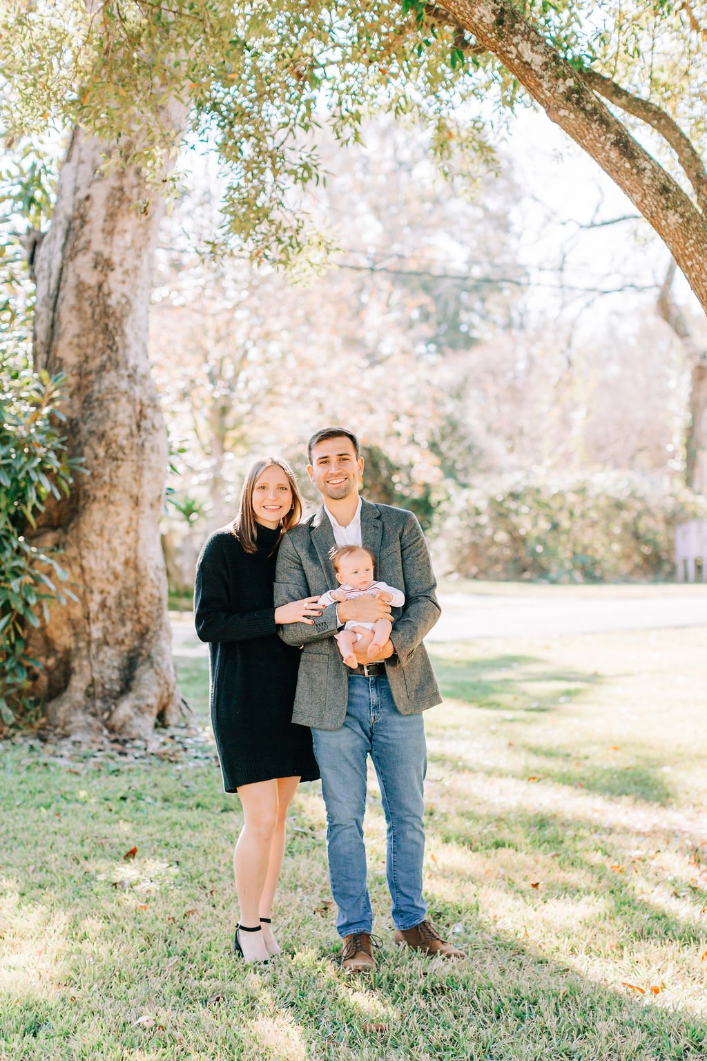 mom standing with dad holding newborn baby during family portrait session in baton rouge