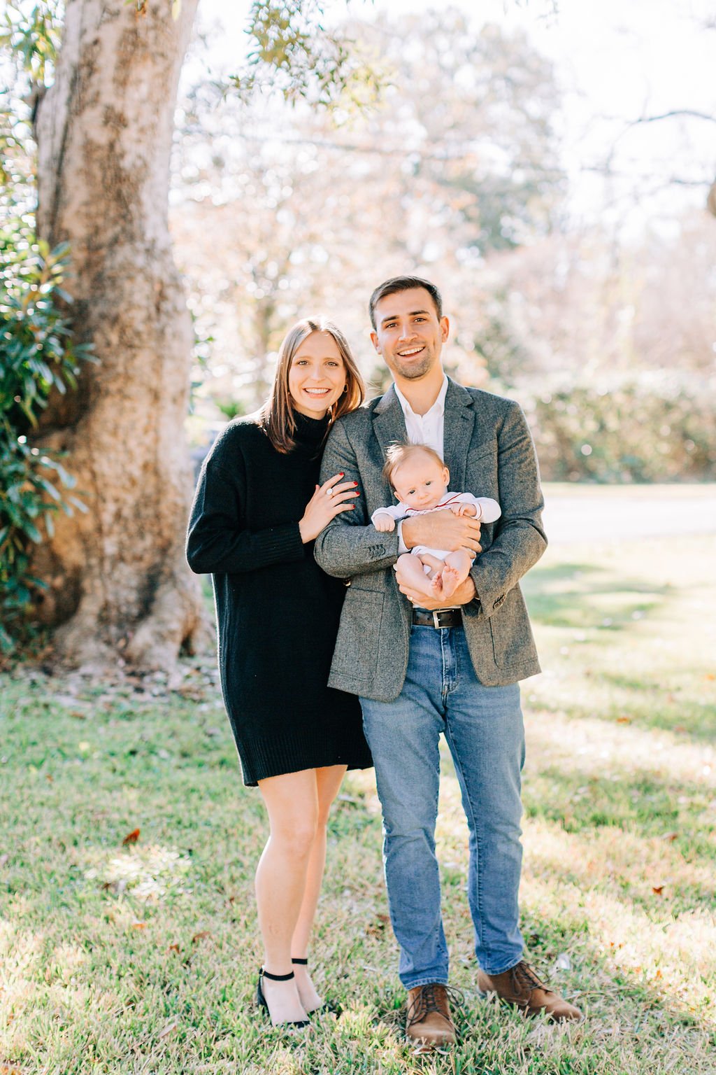mom standing with dad holding newborn baby during family portrait session in baton rouge