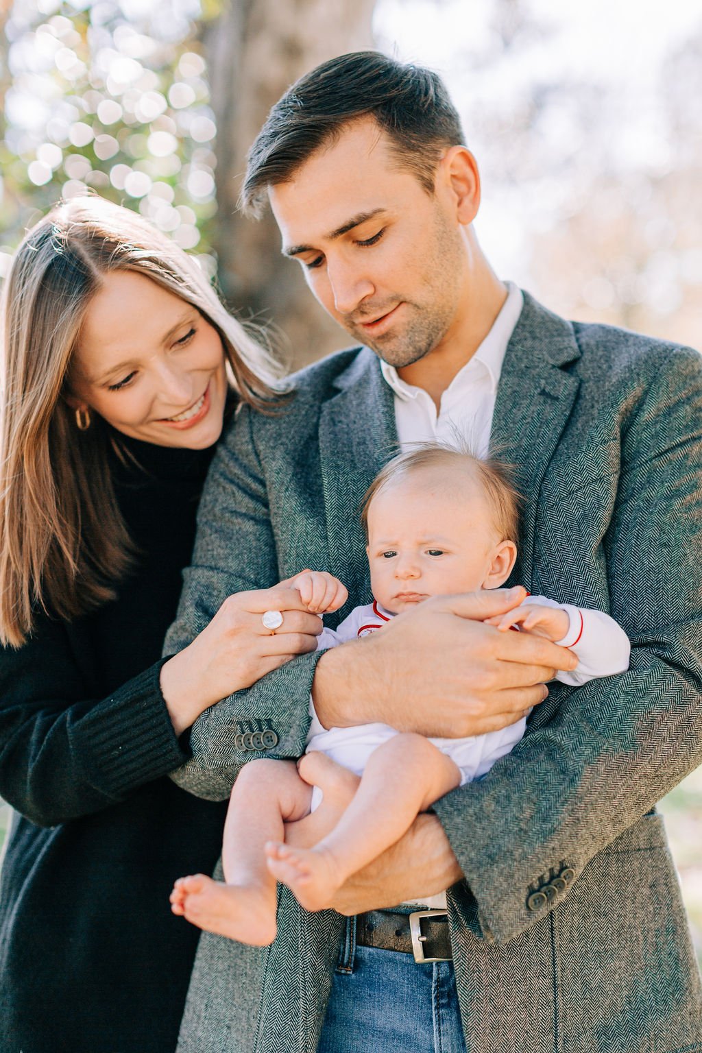 mom standing with dad holding and looking down at newborn baby during family portrait session in baton rouge