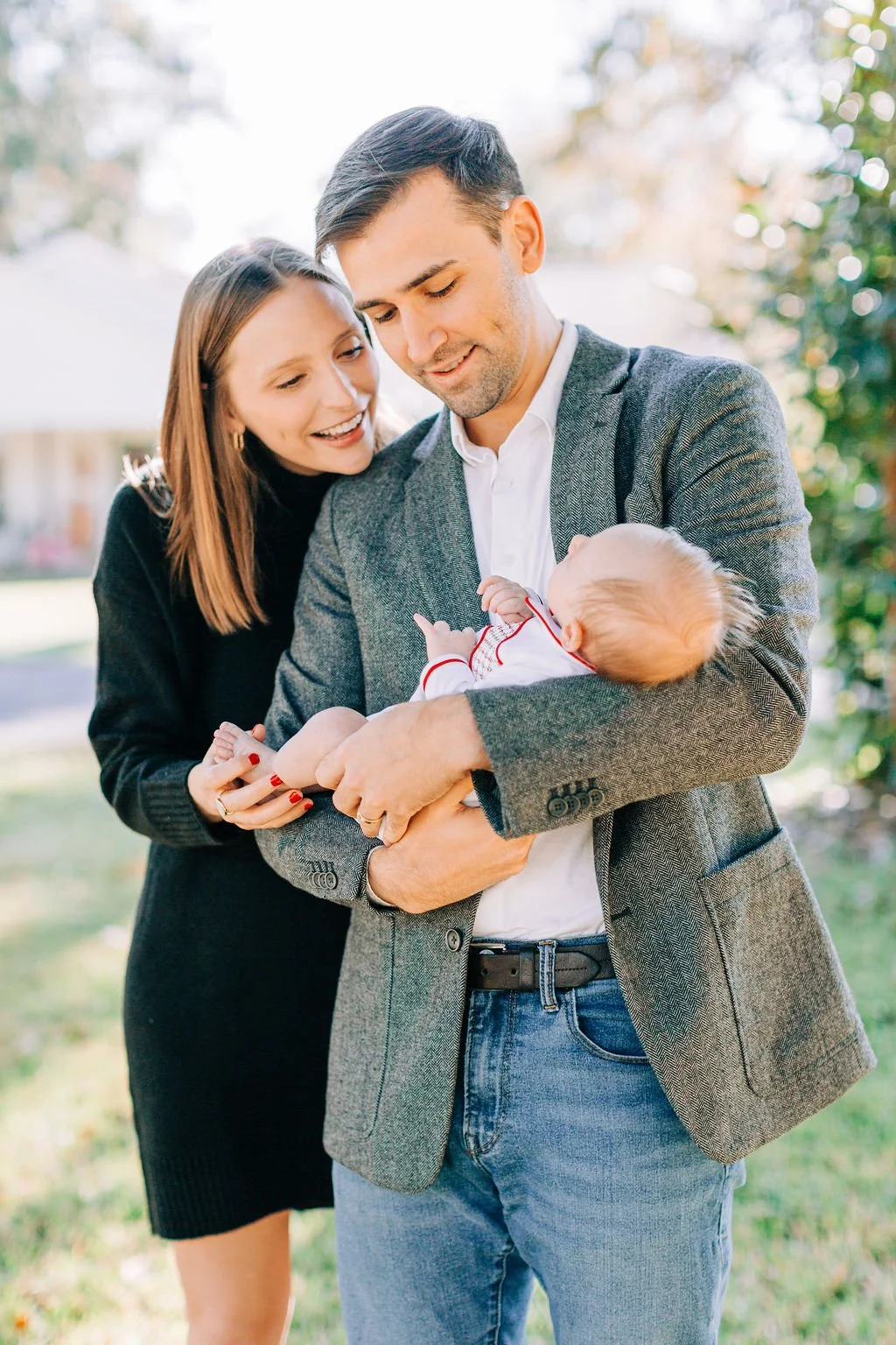 mom standing with dad holding and looking down at newborn baby during family portrait session in baton rouge