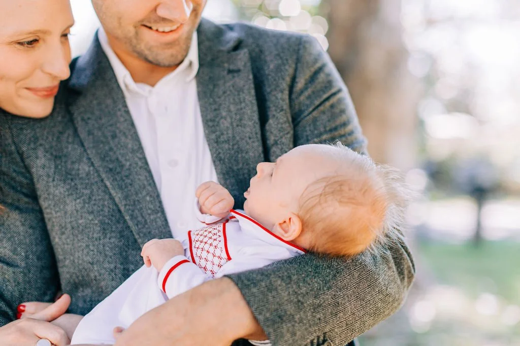 close-up of mom standing with dad holding and looking down at newborn baby during family portrait session in baton rouge