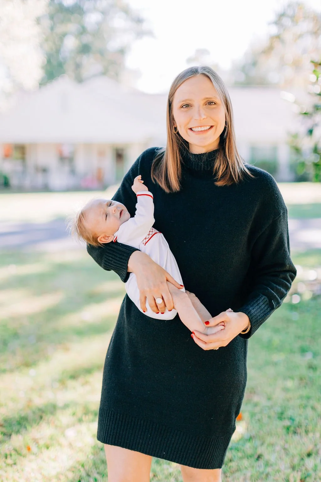 mom standing and holding newborn baby during family portrait session in baton rouge