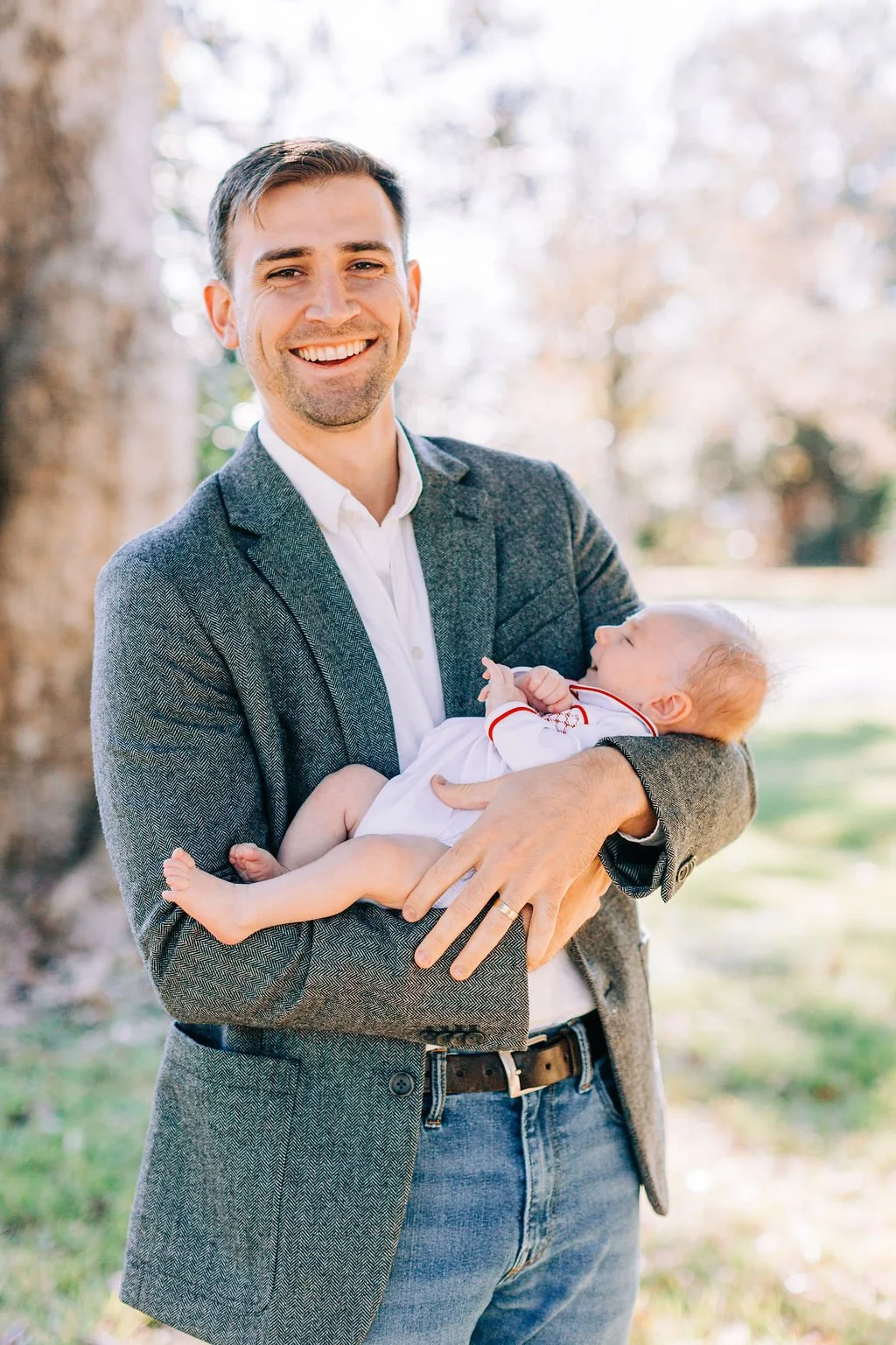 dad standing and holding newborn baby during family portrait session in baton rouge