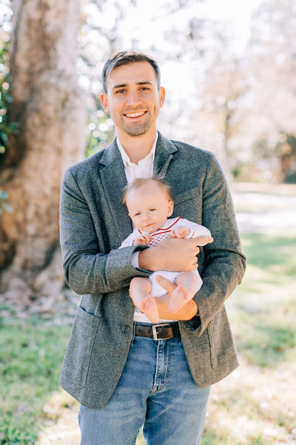 dad standing and holding newborn baby during family portrait session in baton rouge