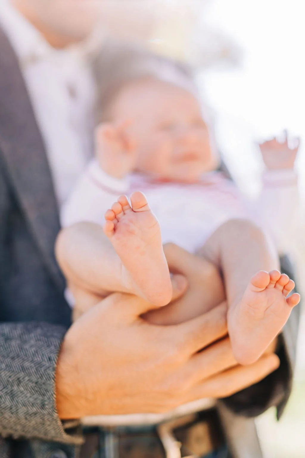 close up of newborn baby boy’s feet while dad holding baby during family portrait session in baton rouge