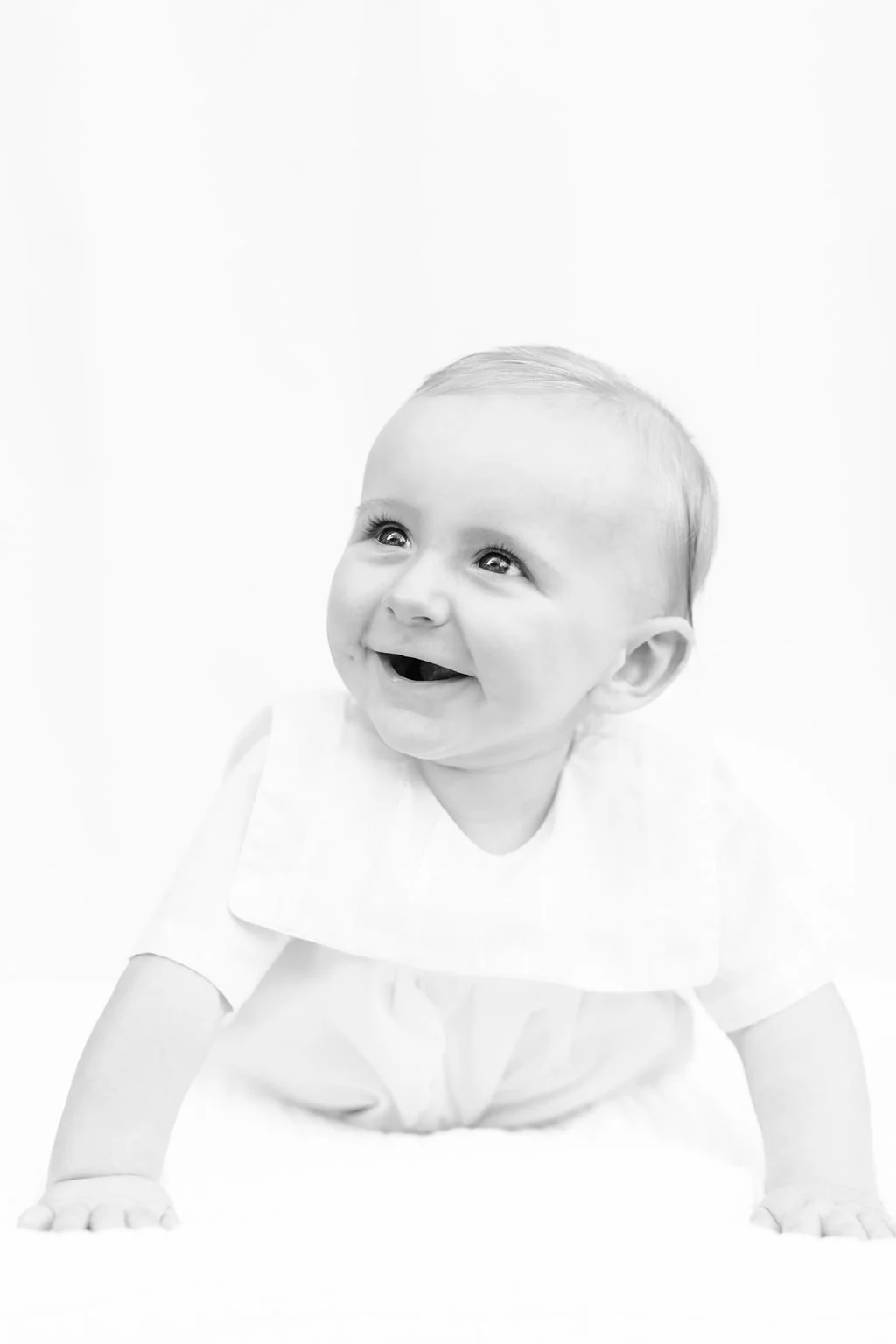 6 month baby boy smiling during milestone session in Baton Rouge with white backdrop