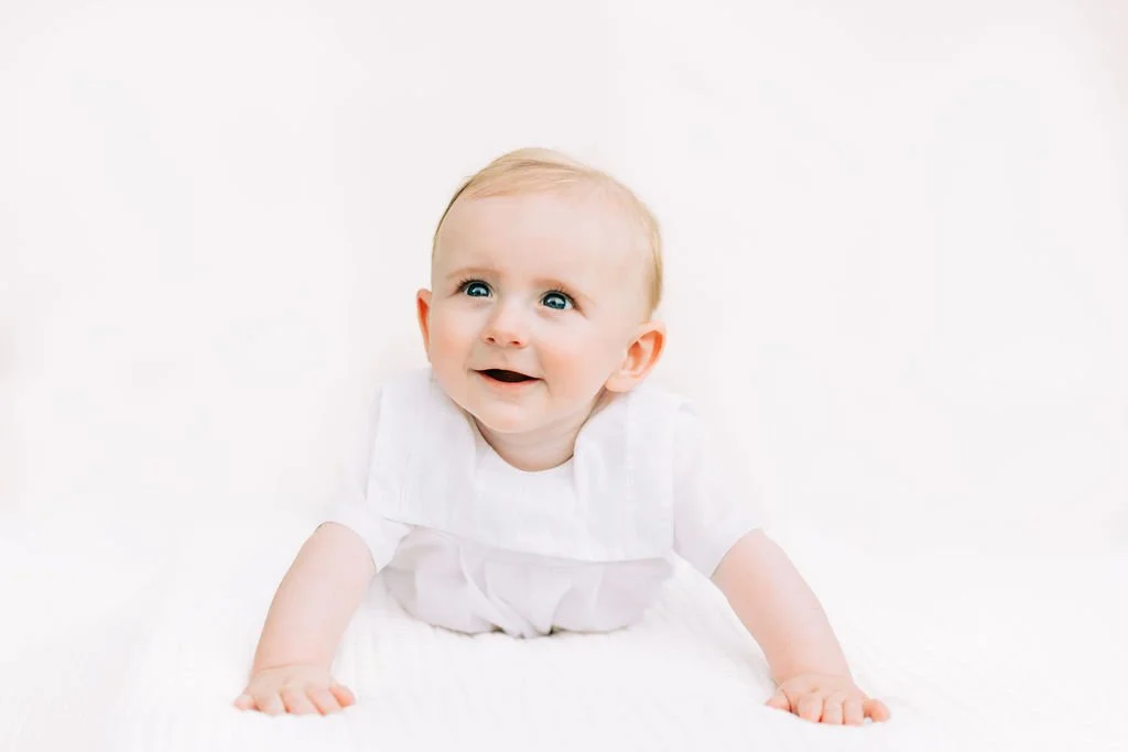6 month baby boy smiling during milestone session in Baton Rouge with white backdrop